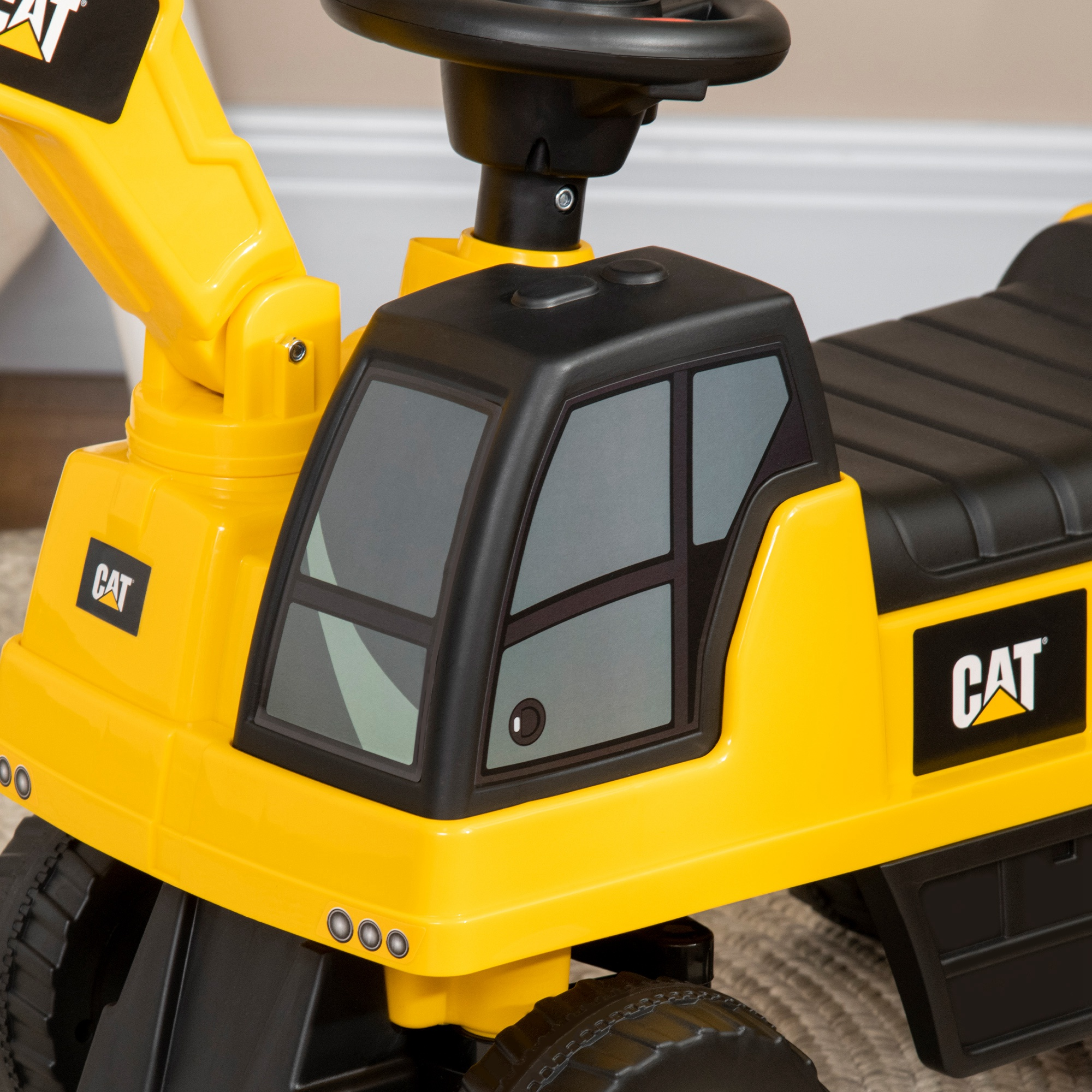 Primo piano di un giocattolo escavatore CAT giallo. Dettagli neri sulla cabina e un logo CAT.