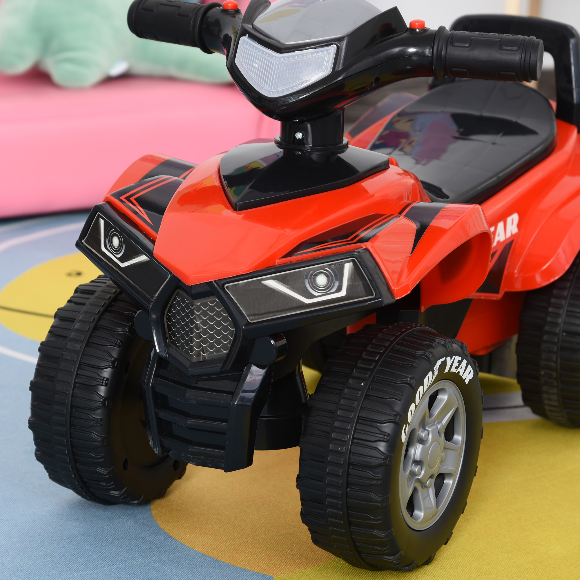 ATV giocattolo rosso con dettagli neri. L'ATV ha le parole “GOOD YEAR” sui suoi pneumatici. Sfondo giallo e rosa.