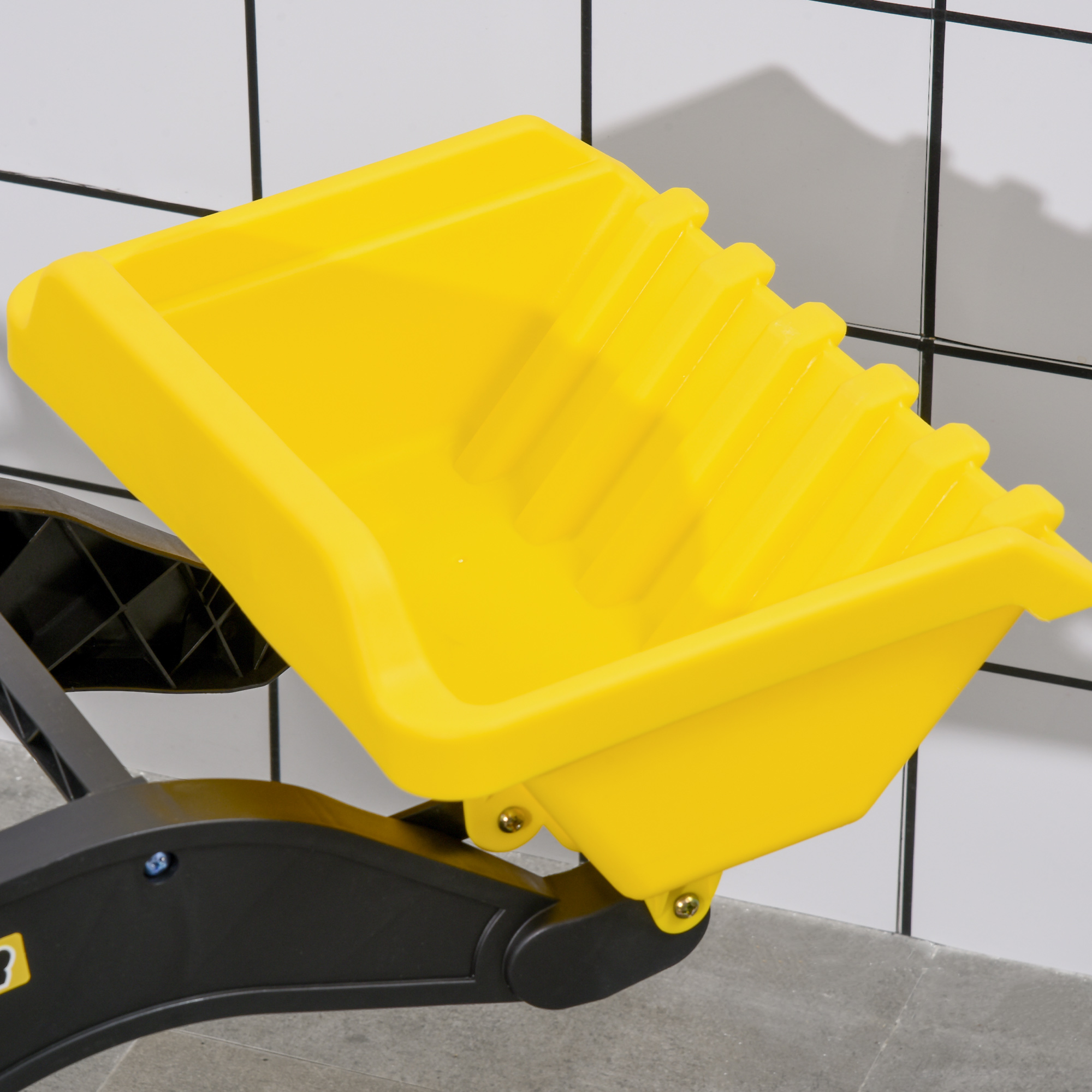 Benna dell'escavatore giocattolo giallo attaccata al braccio nero. La benna è inclinata verso l'alto.