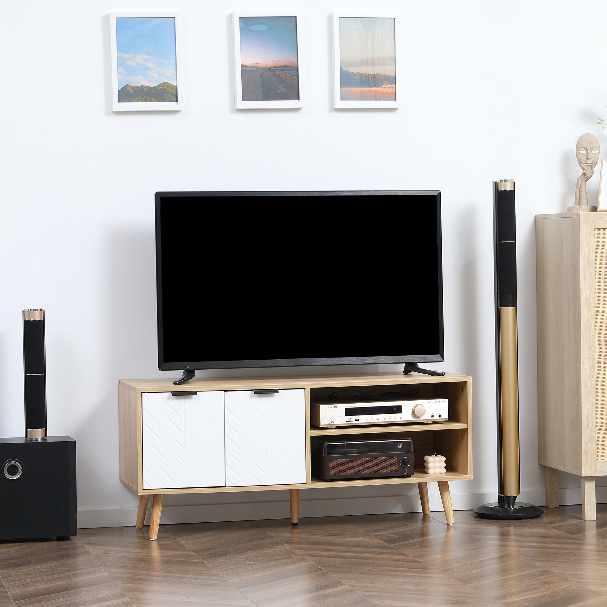 Mueble de TV con TV, altavoces y decoración. TV sobre mueble con puertas blancas. Altavoces a los lados.