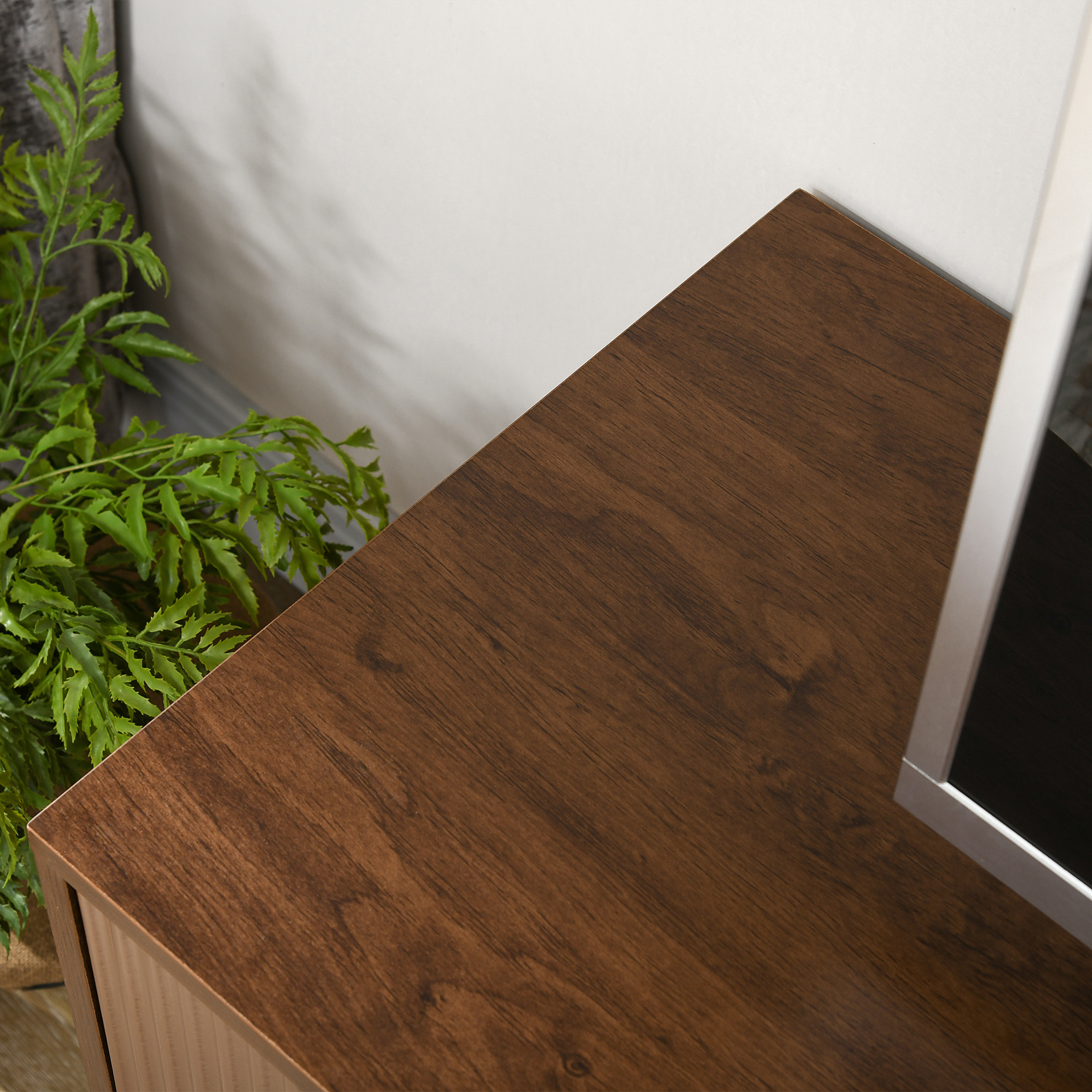 Primo piano della superficie di un mobile in legno marrone con una pianta verde nell'angolo.