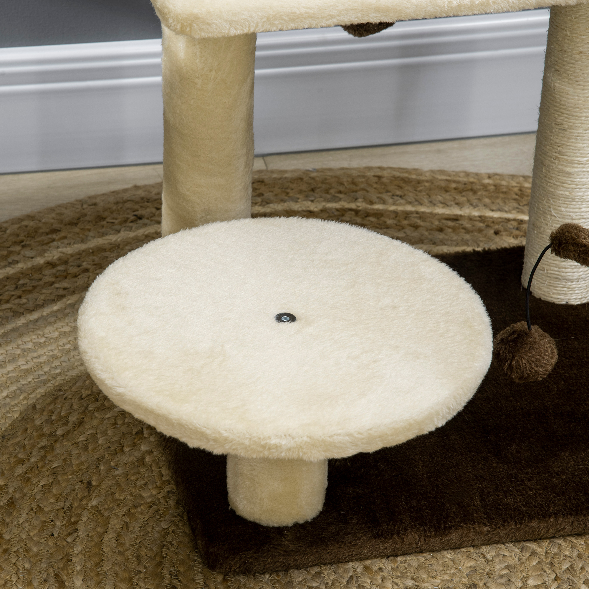 Primo piano della piattaforma dell'albero per gatti. Una piattaforma rotonda beige con superficie morbida. Tappeto marrone e palo.