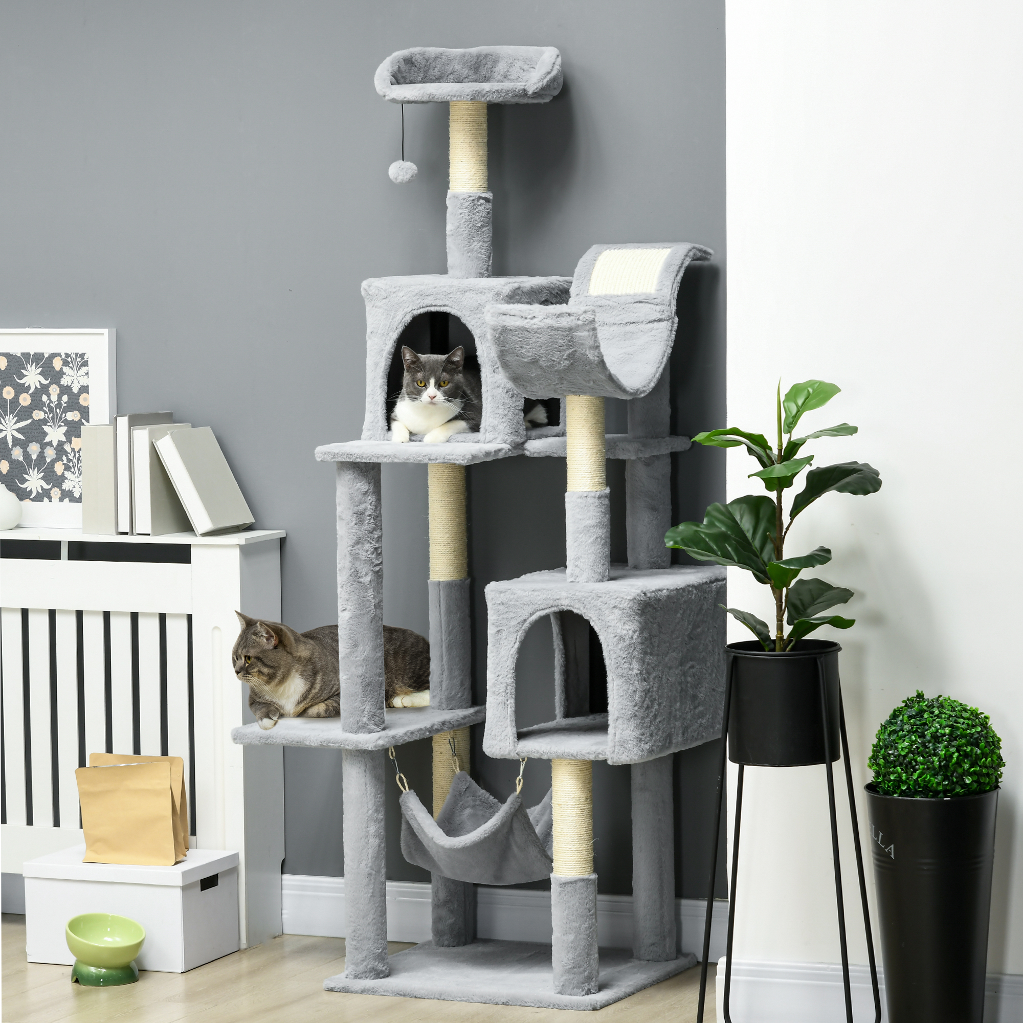Albero per gatti con più gatti e alcuni oggetti sullo sfondo.