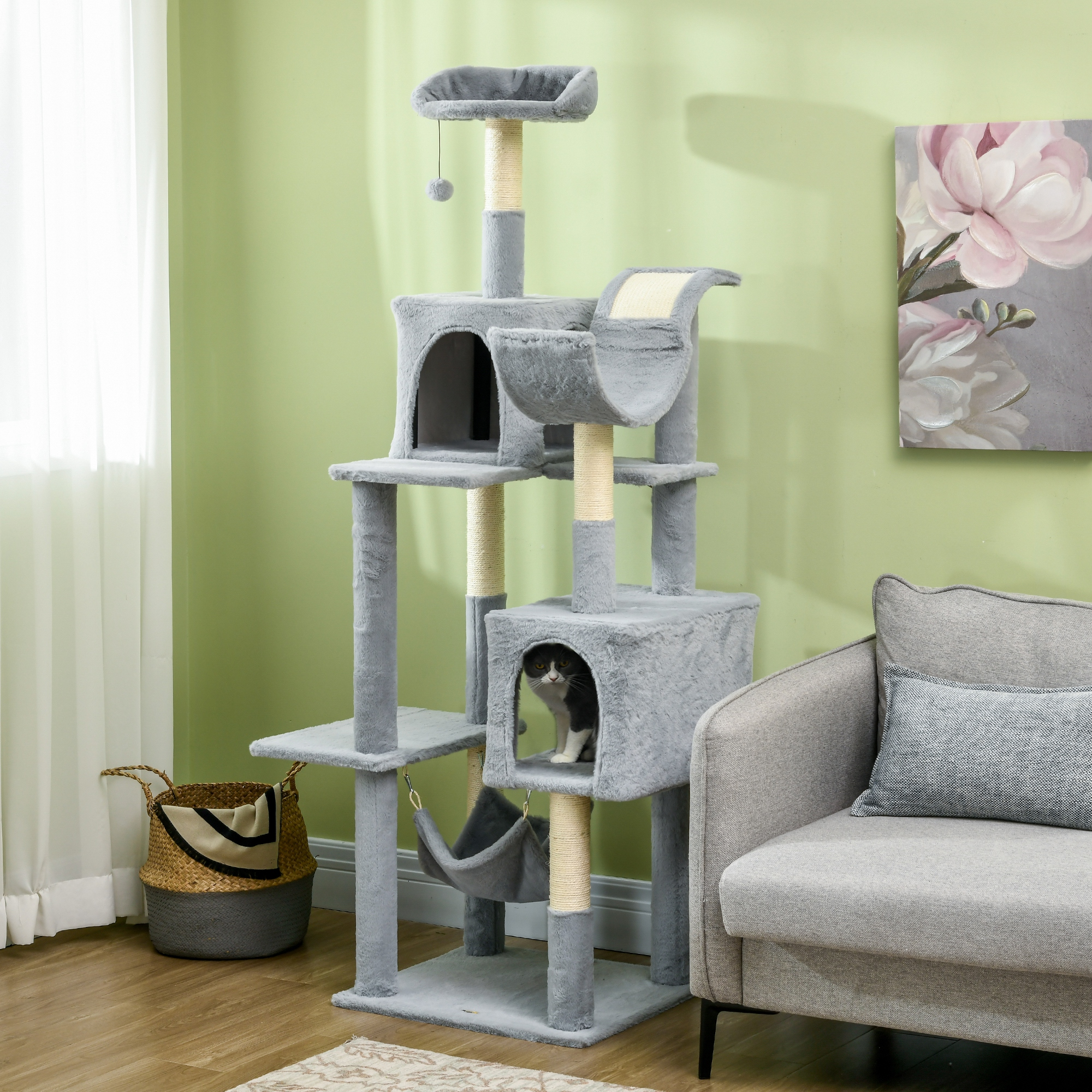 Un albero per gatti grigio con più livelli. Un gatto è nel cubo. Divano sullo sfondo.