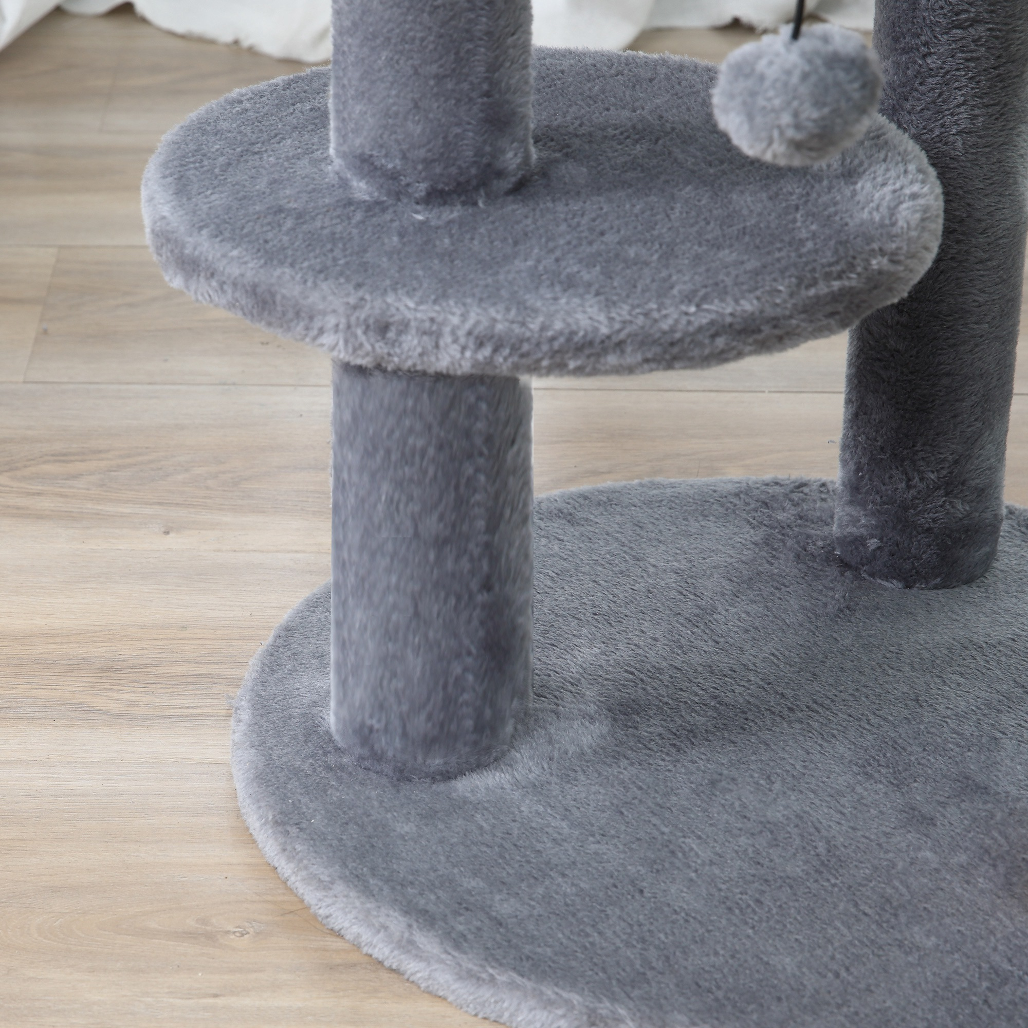 Primo piano delle piattaforme e dei tiragraffi di un albero per gatti. La base è grigia e di legno.