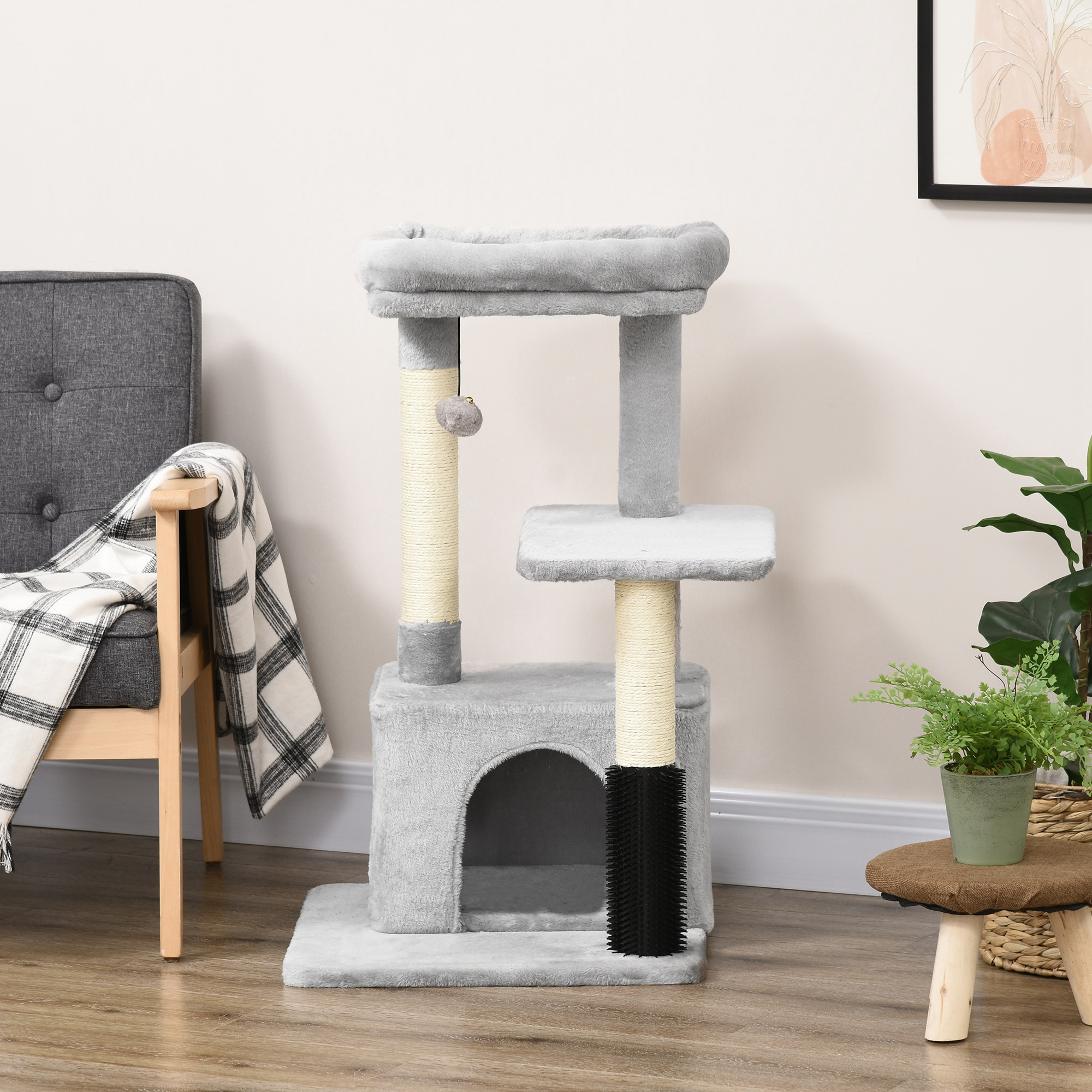Un albero per gatti grigio con più livelli, una grotta e un giocattolo pendente, contro un muro.