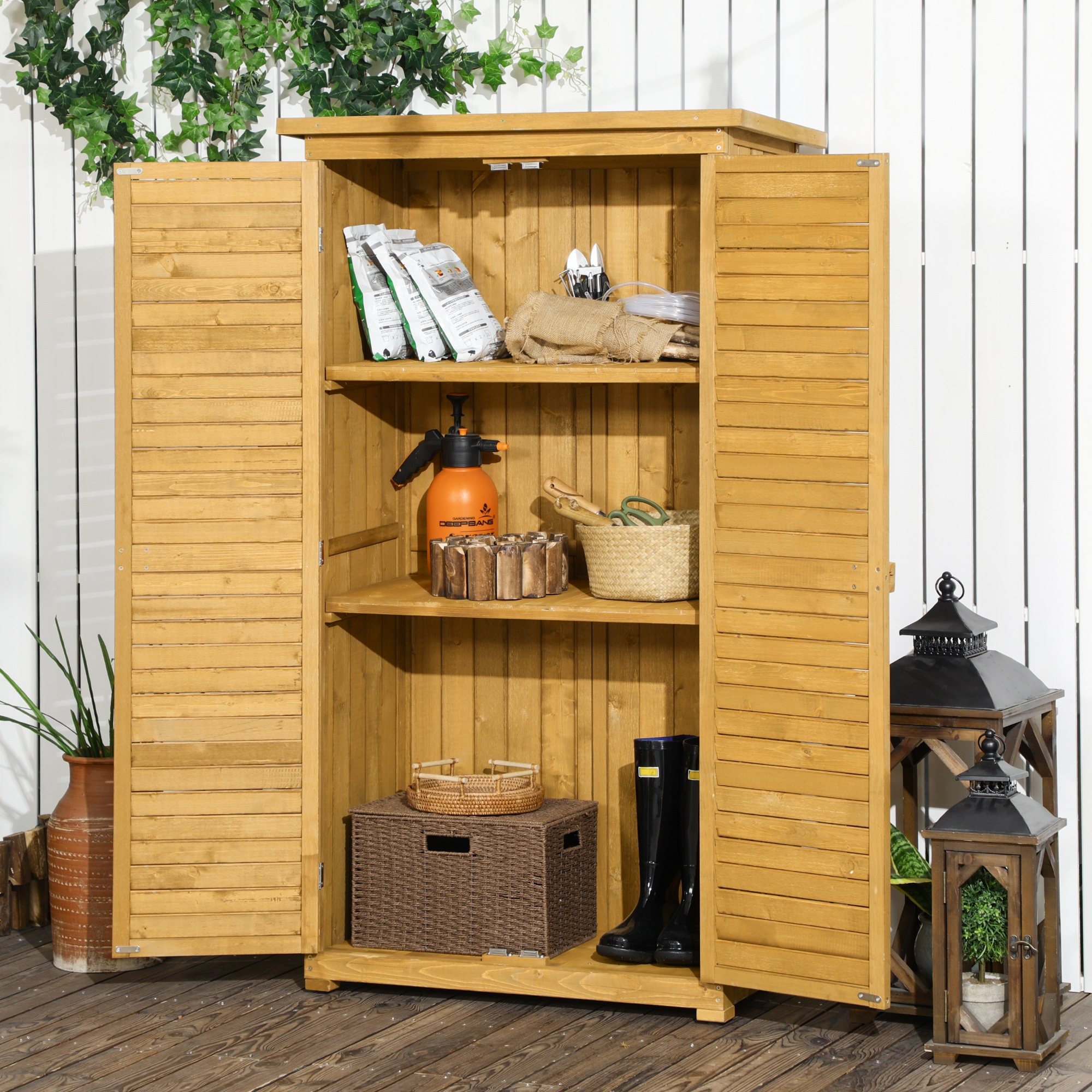 Mobile in legno con ante aperte, ripiani con forniture per il giardinaggio e un vaso di fiori, su un terrazzo in legno.
