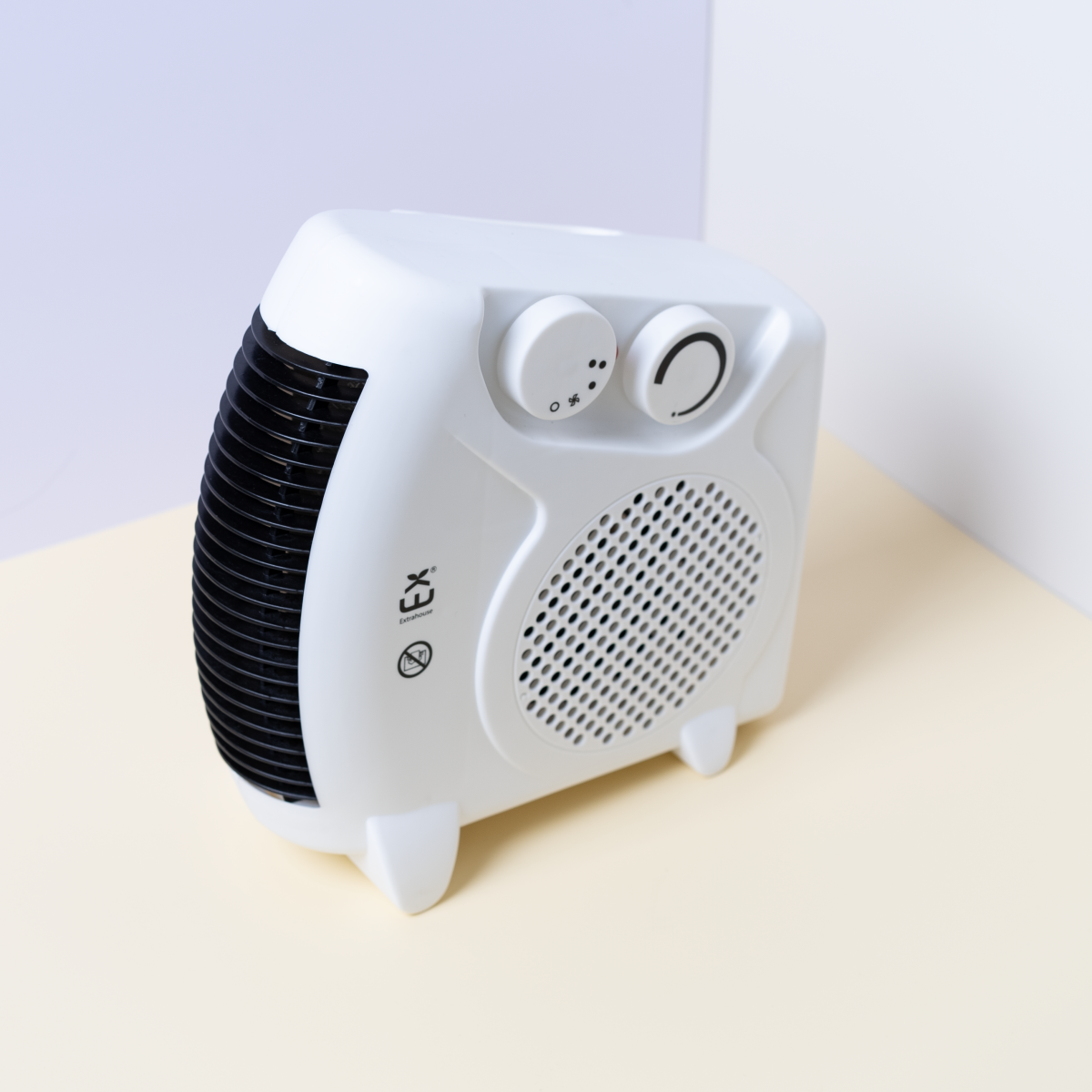 Un calefactor eléctrico blanco y negro contra una superficie amarillo claro.
