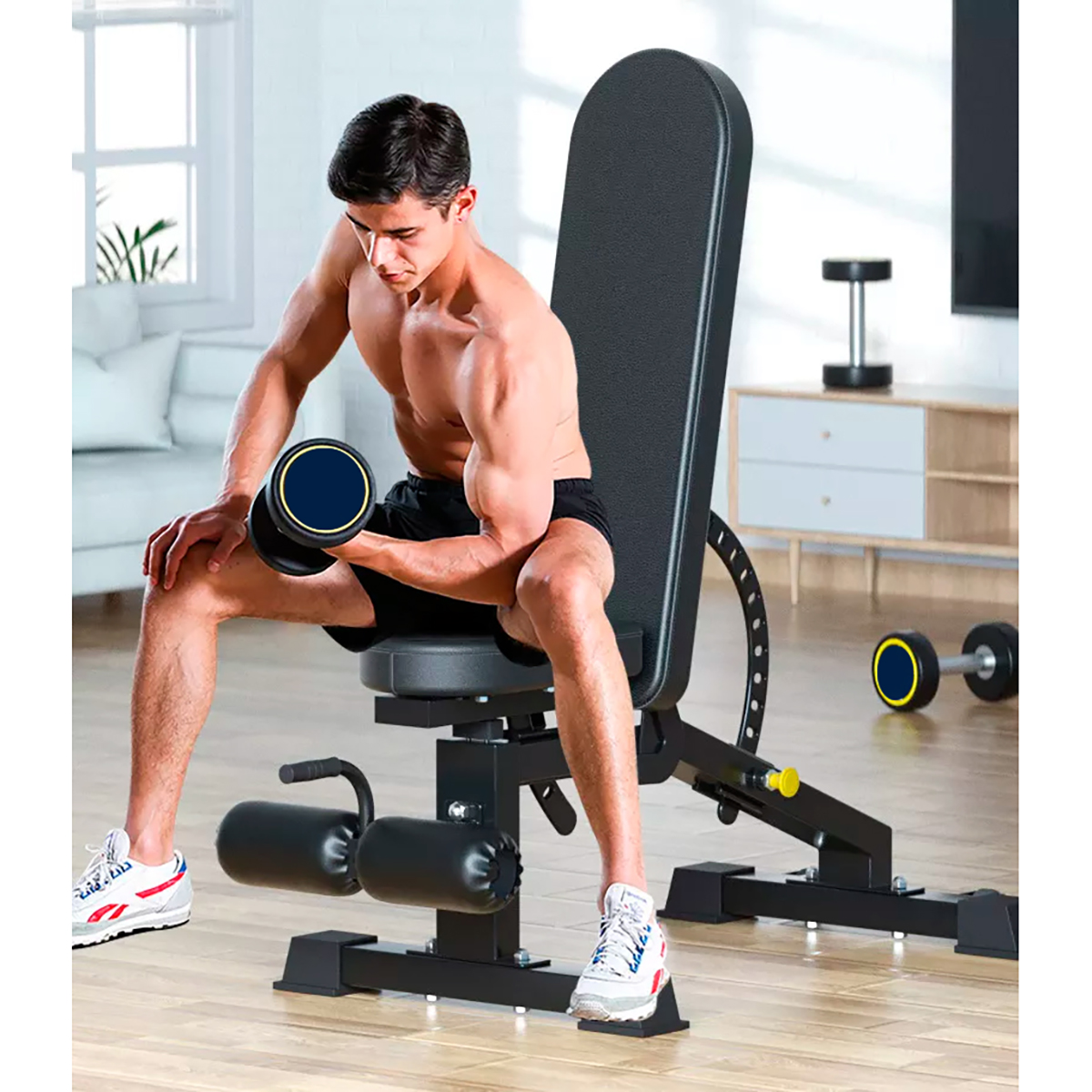 Een man tilt een halter op terwijl hij op een zwarte bank in een fitnessruimte thuis zit.