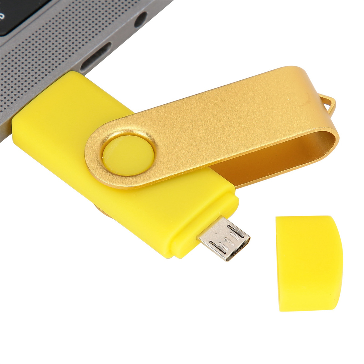 Gelber und goldener USB-Stick, der an einen Laptop angeschlossen ist. Die Kappe liegt daneben.