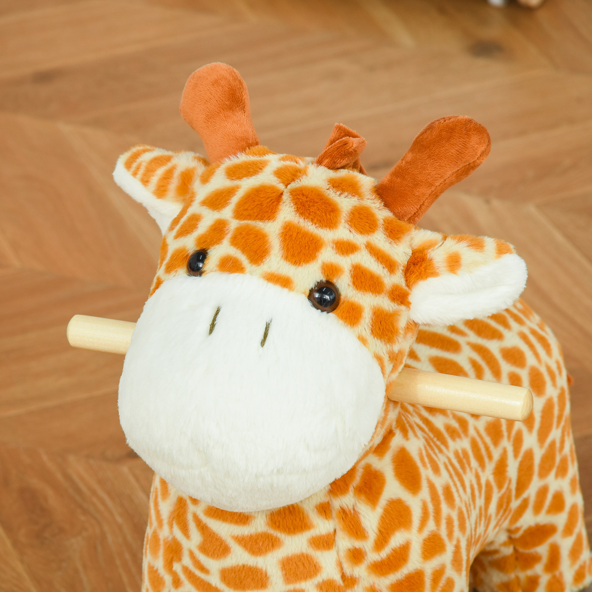 Un giocattolo a dondolo a forma di giraffa con macchie arancioni e gialle su pavimento in legno marrone.
