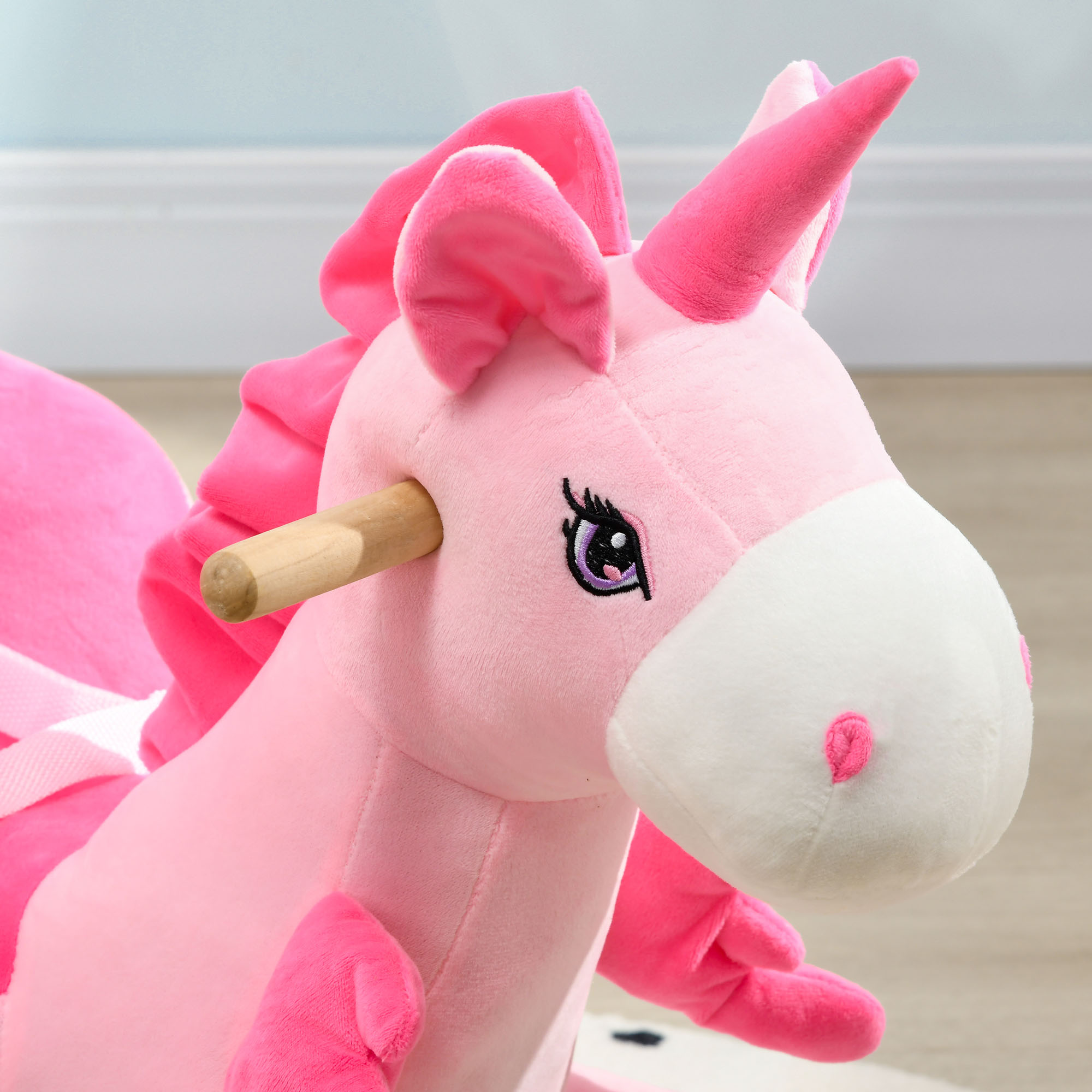 Primo piano di un cavallo a dondolo unicorno rosa. Naso bianco, corno rosa e ciglia nere.