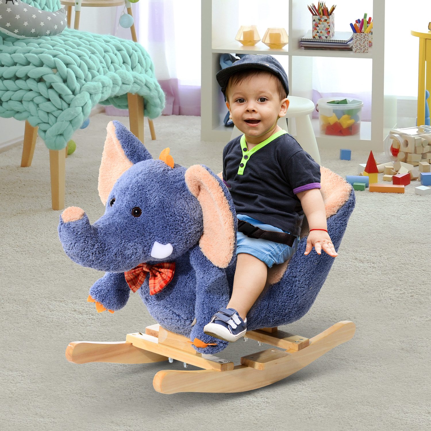 Un bambino su un giocattolo a dondolo a forma di elefante blu, con papillon, in un ambiente sala giochi.