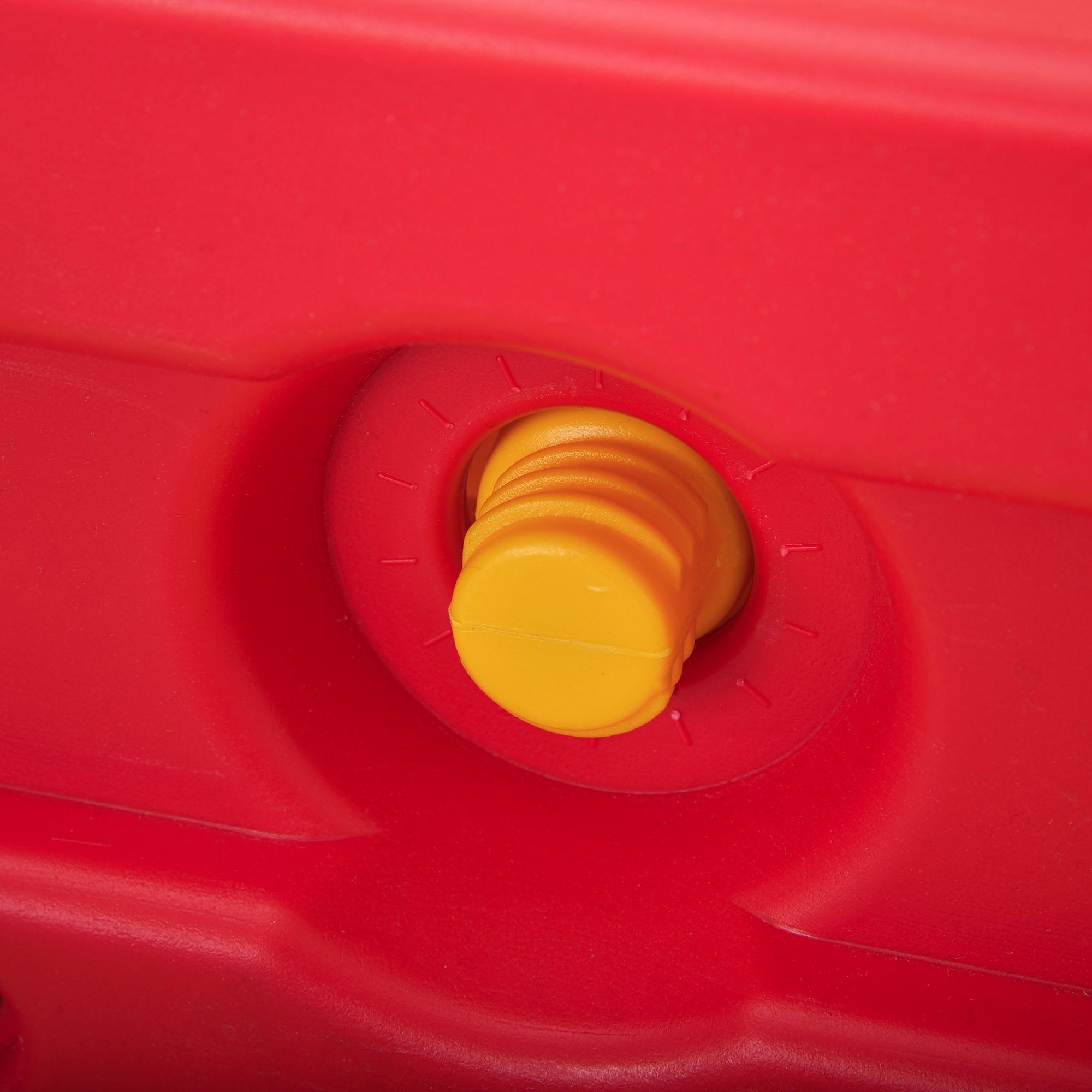 Un primo piano di un pezzo di plastica rosso con un pezzo giallo a forma di tappo inserito.
