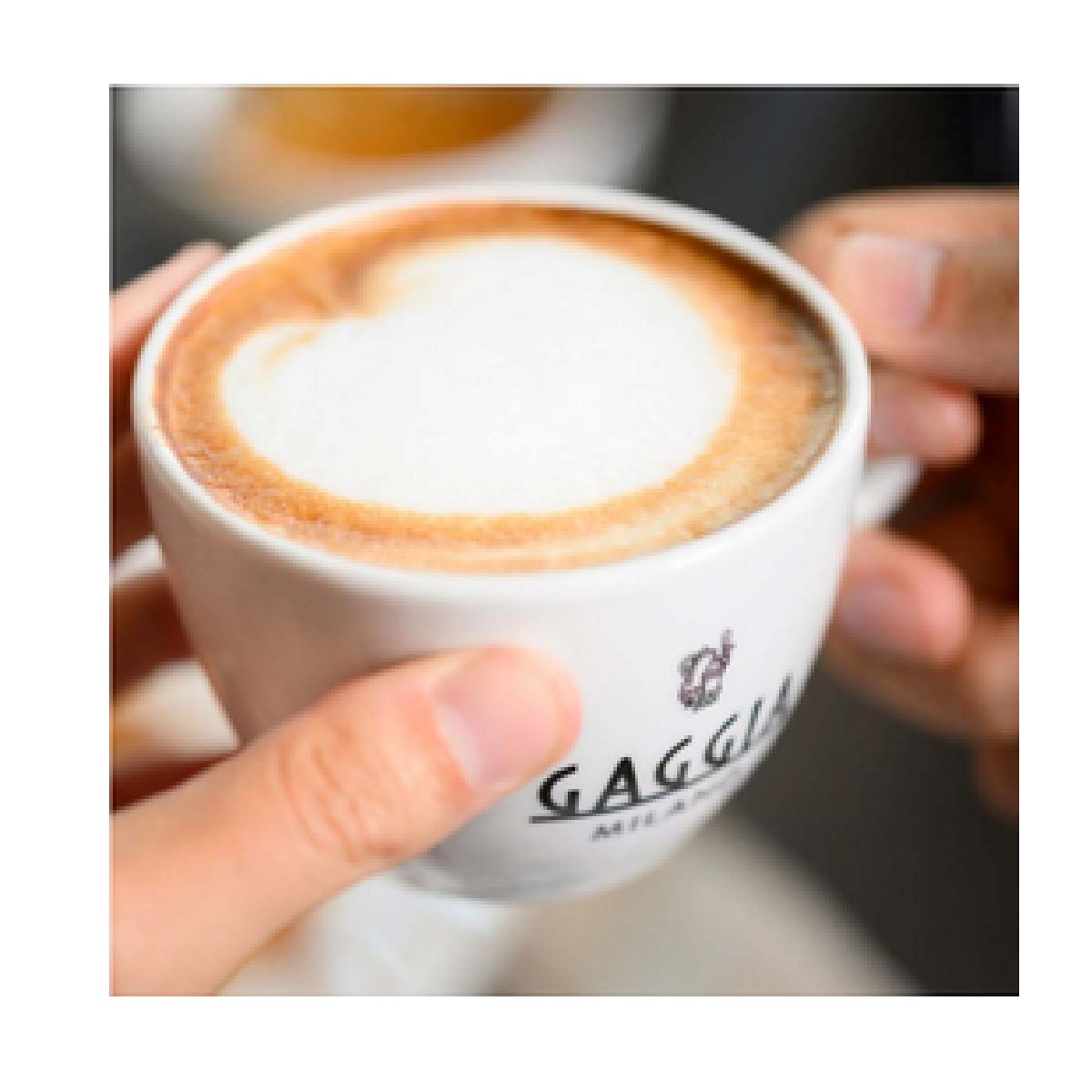 Filiżanka cappuccino z sercem w pianie, trzymana przez dwie ręce.