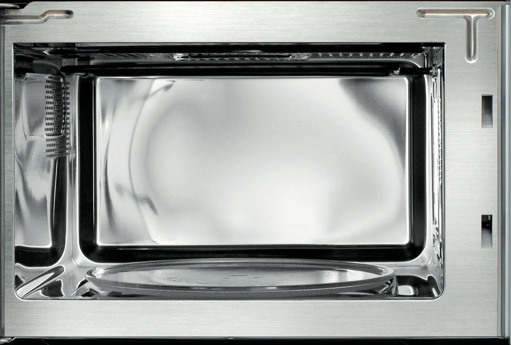 Interno di un forno a microonde. Interno argentato con piatto in vetro. Il telaio è anch'esso argentato.