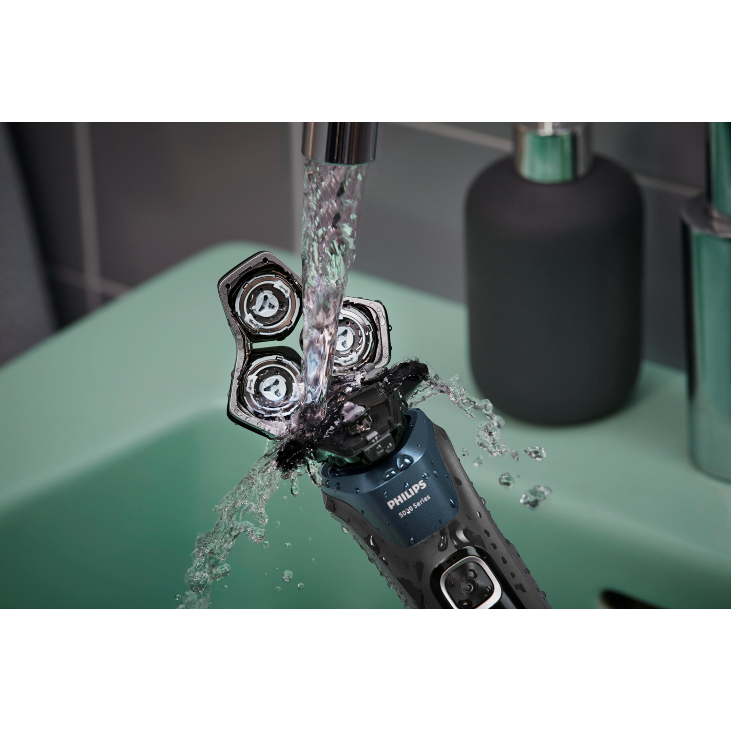 Golarka Philips jest płukana pod kranem, z kroplami wody. Scena rozgrywa się w łazience.