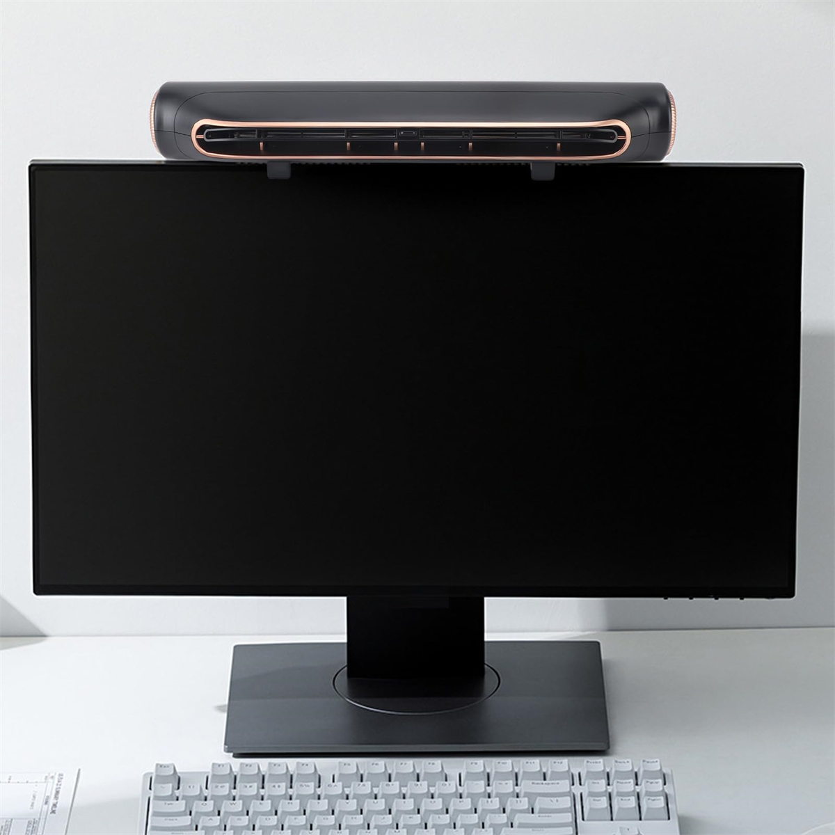 Ein schwarzer Monitor mit einer Soundbar oben. Im Vordergrund eine weiße Tastatur.
