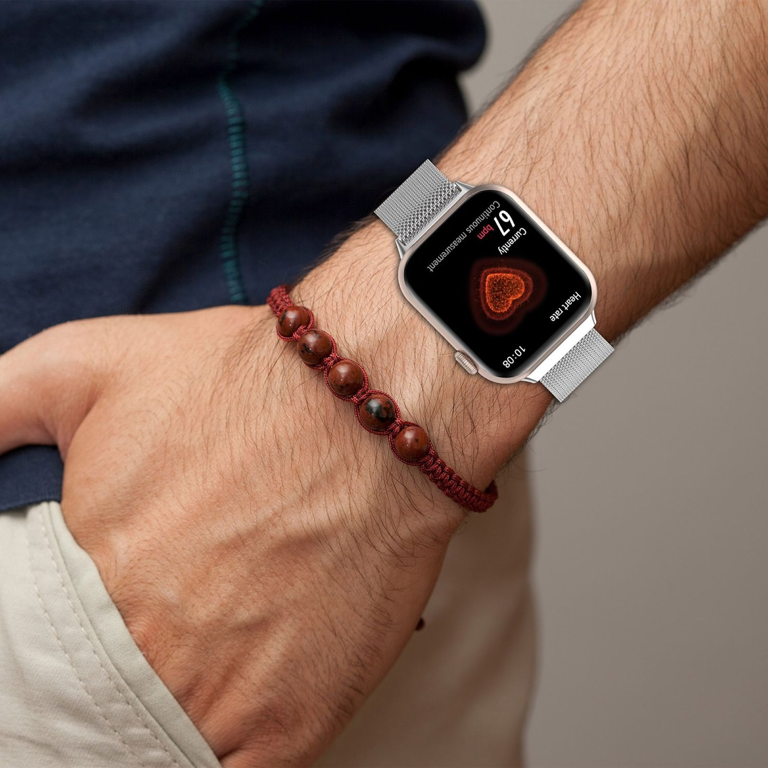 Handgelenk mit Smartwatch mit Herzfrequenz und Perlenarmband.