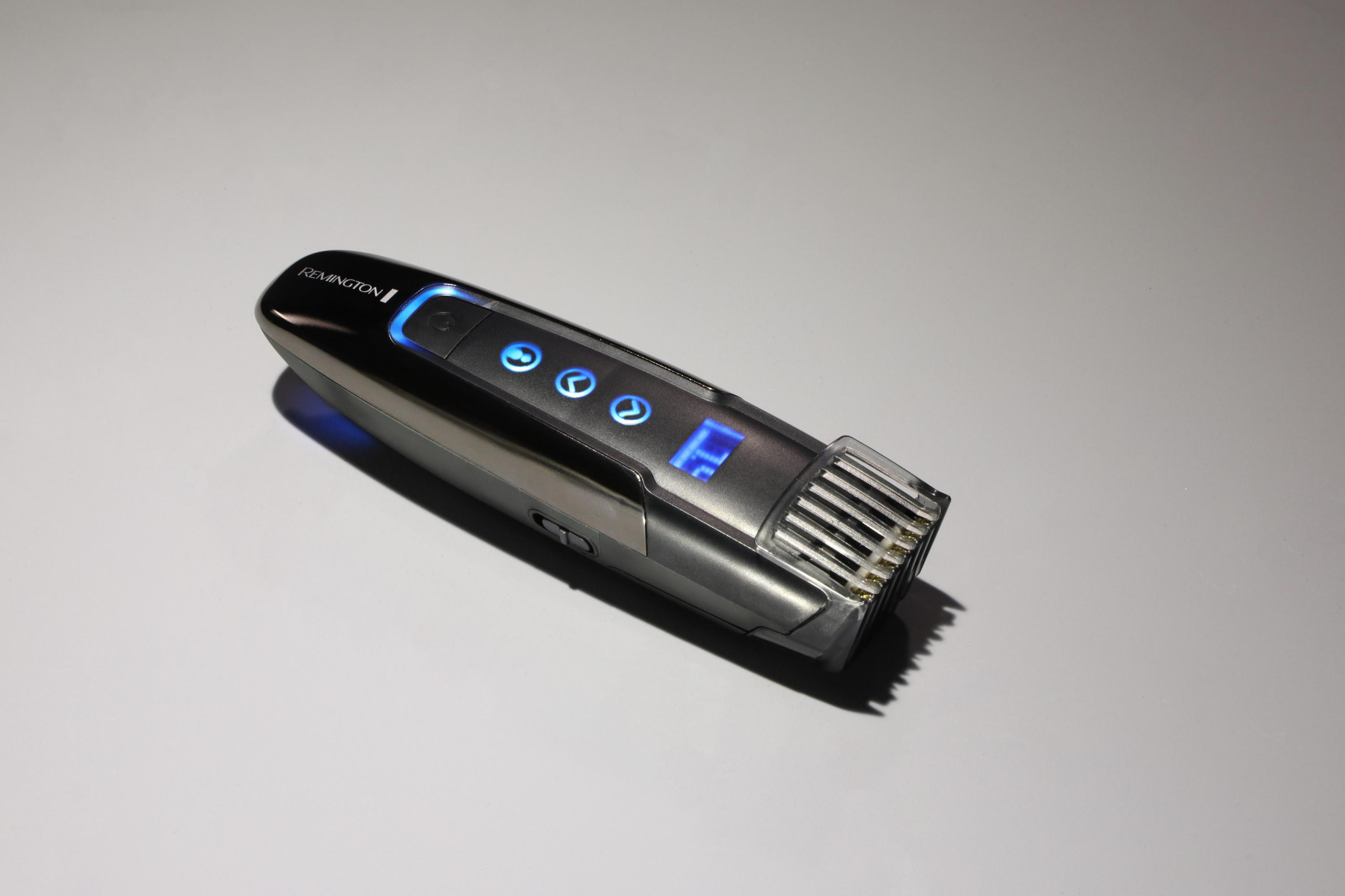 Recortadora Remington plateada y negra sobre una superficie blanca, con botones iluminados azules.