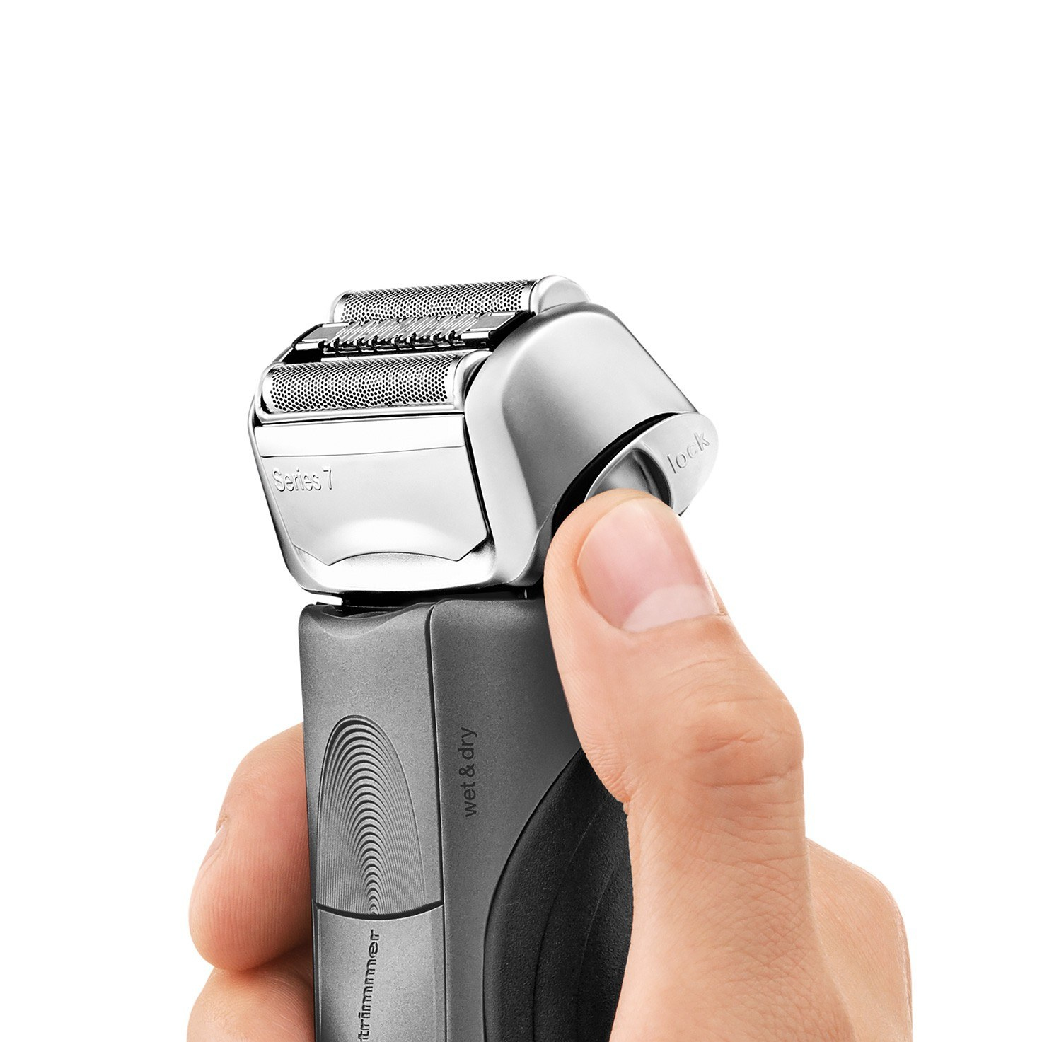 Dłoń trzymająca srebrną golarkę elektryczną z otwartą głowicą na białym tle.