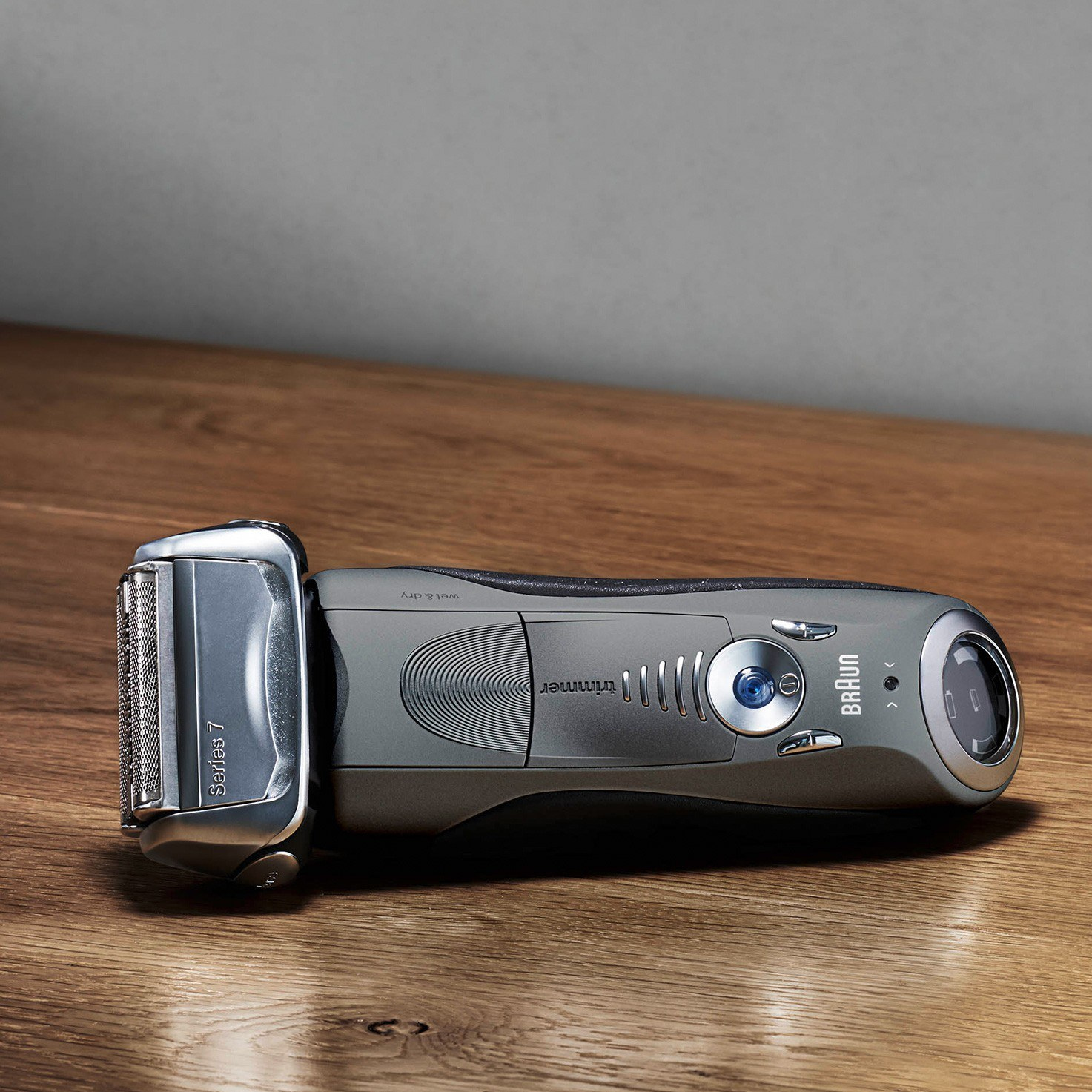 Szara i srebrna golarka elektryczna na drewnianej powierzchni. Golarka w centrum.