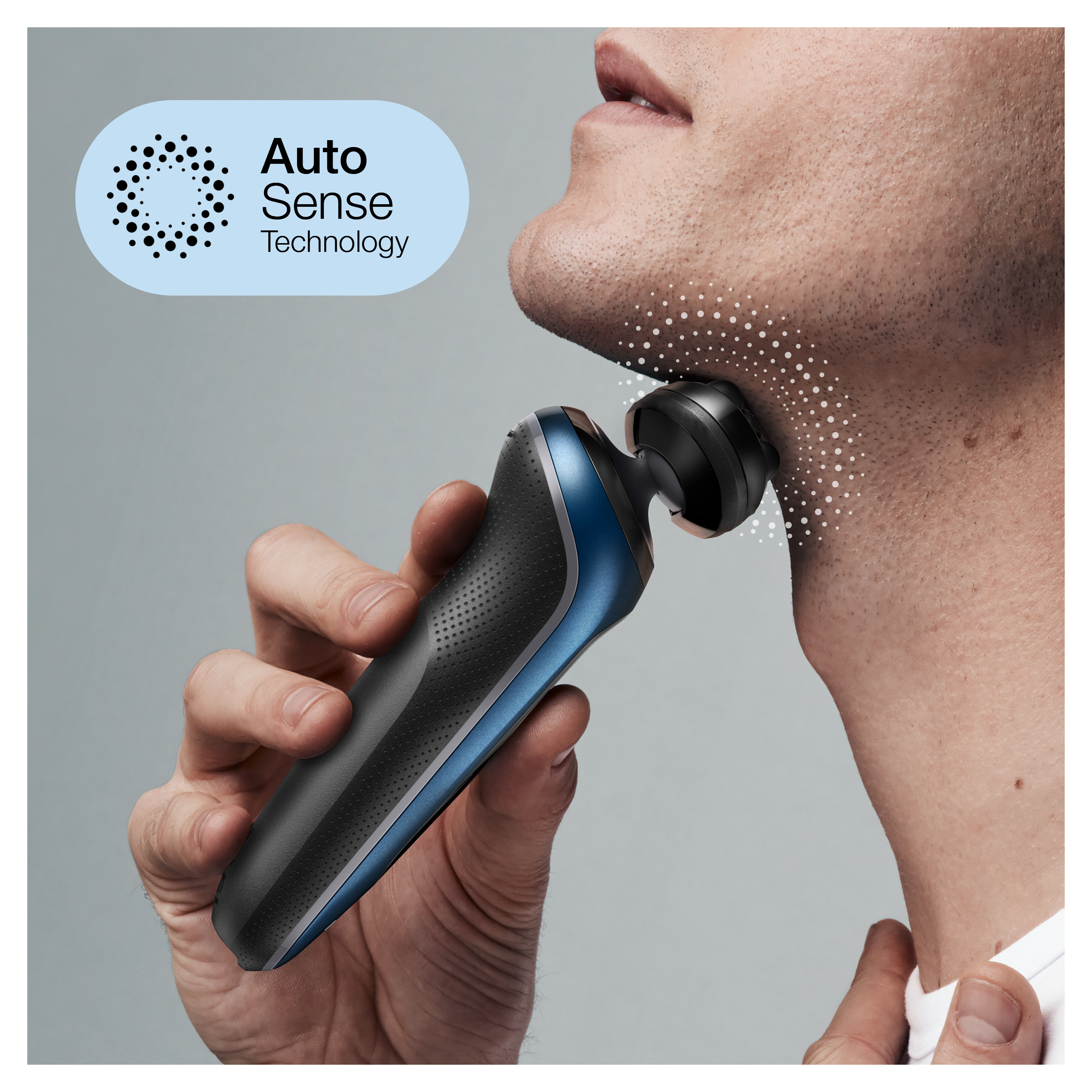 Mężczyzna golący się czarno-niebieską golarką elektryczną na szarym tle.