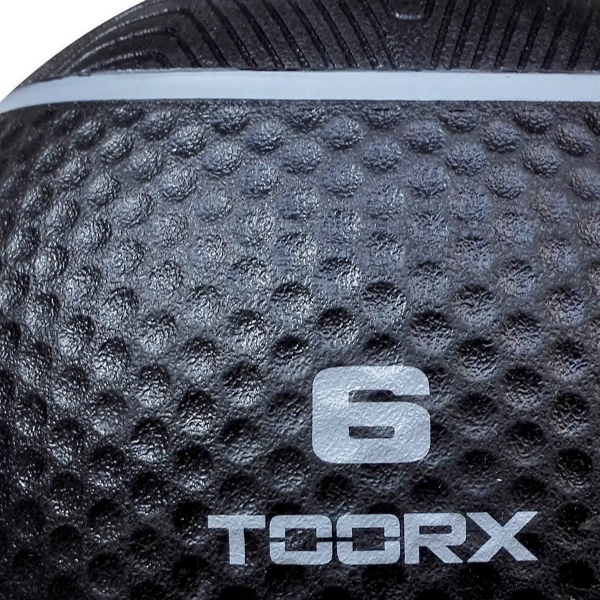 Gros plan sur un ballon médicinal noir avec le numéro 6 et le logo TOORX. Surface texturée.
