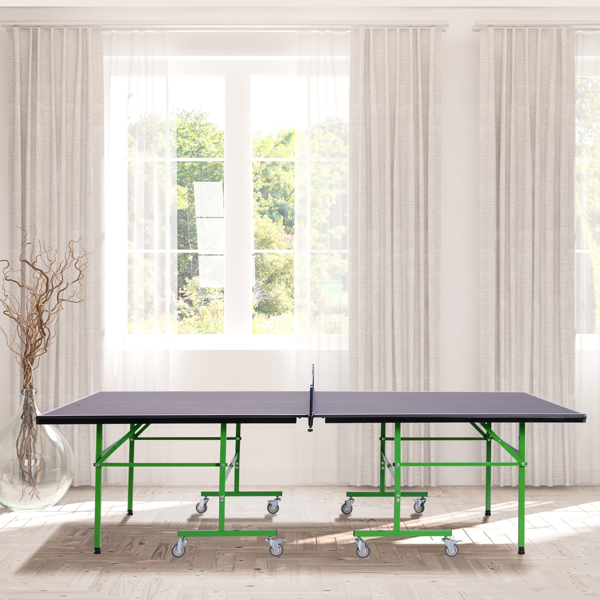Un tavolo da ping pong con gambe verdi, piano nero e una rete. Si trova in una stanza ben illuminata con una finestra.
