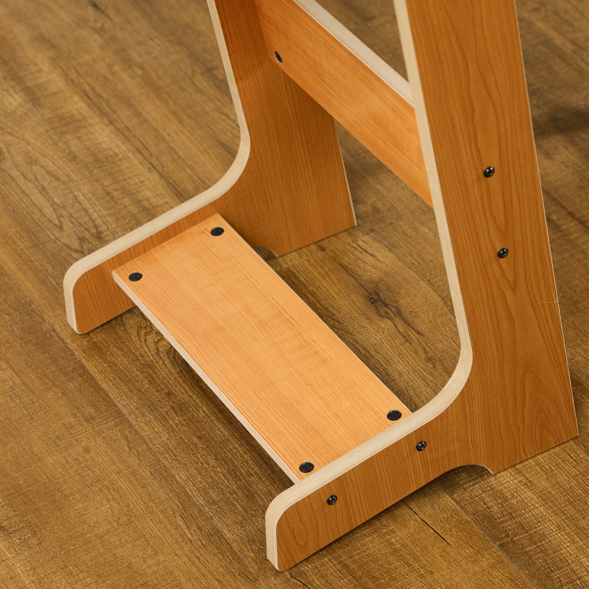 Primo piano di uno sgabello in legno. Lo sgabello è di colore legno chiaro ed è su un pavimento in legno.