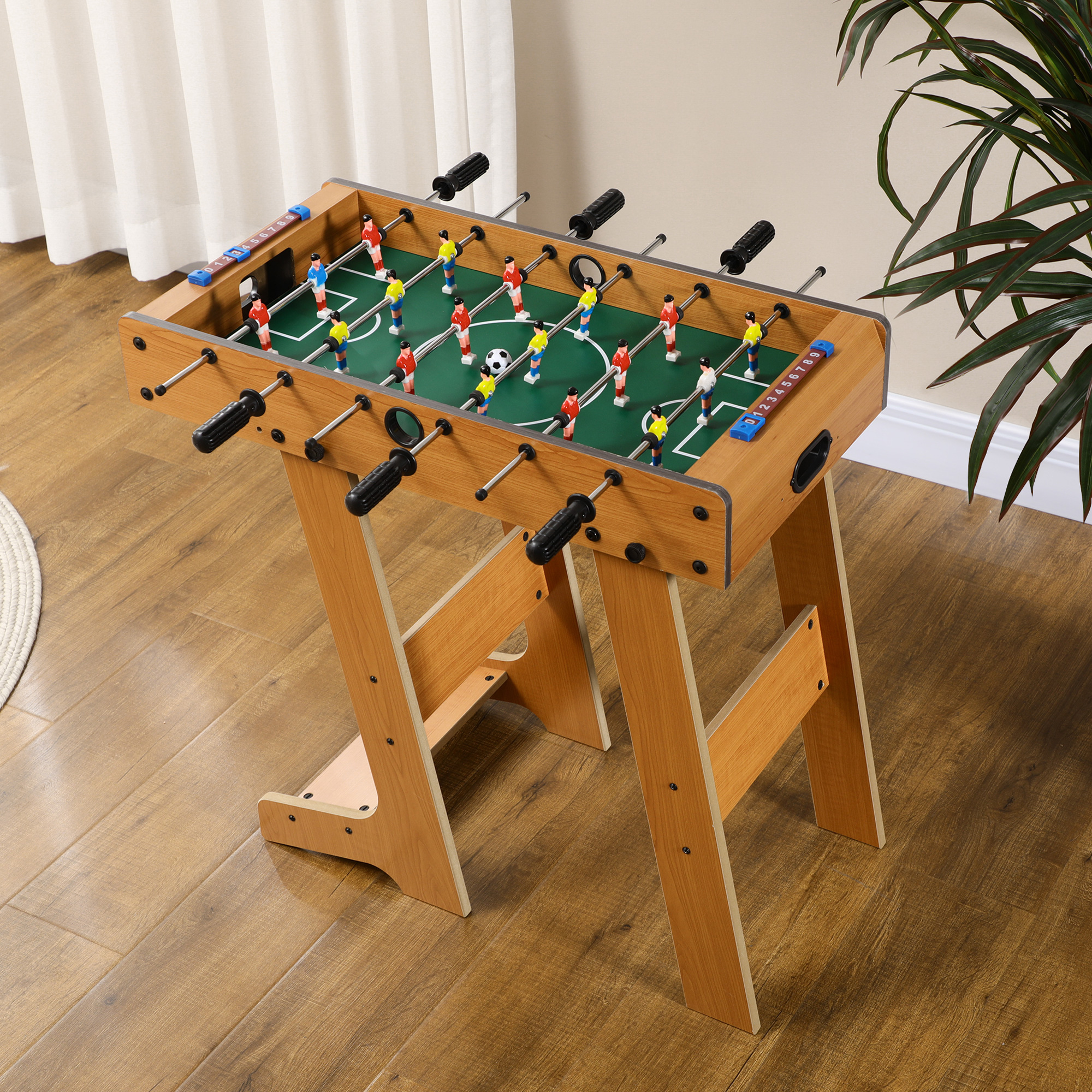 Tavolo da biliardino in una stanza, con un campo da gioco verde e giocatori.