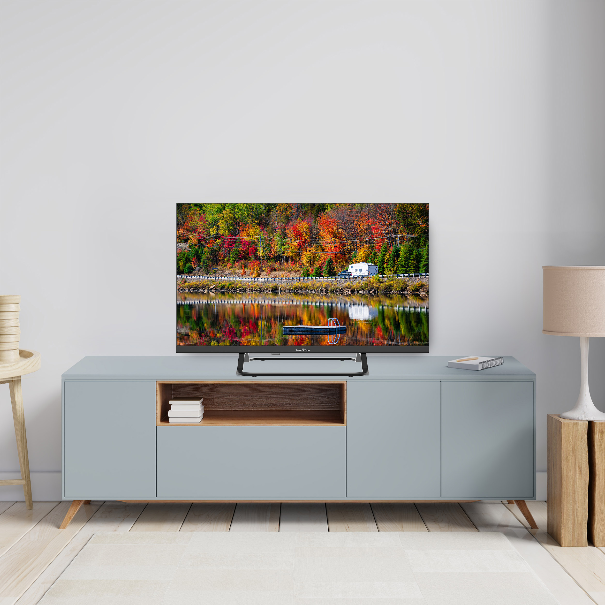 Una TV che mostra una scena autunnale colorata su un mobile blu con decorazioni.