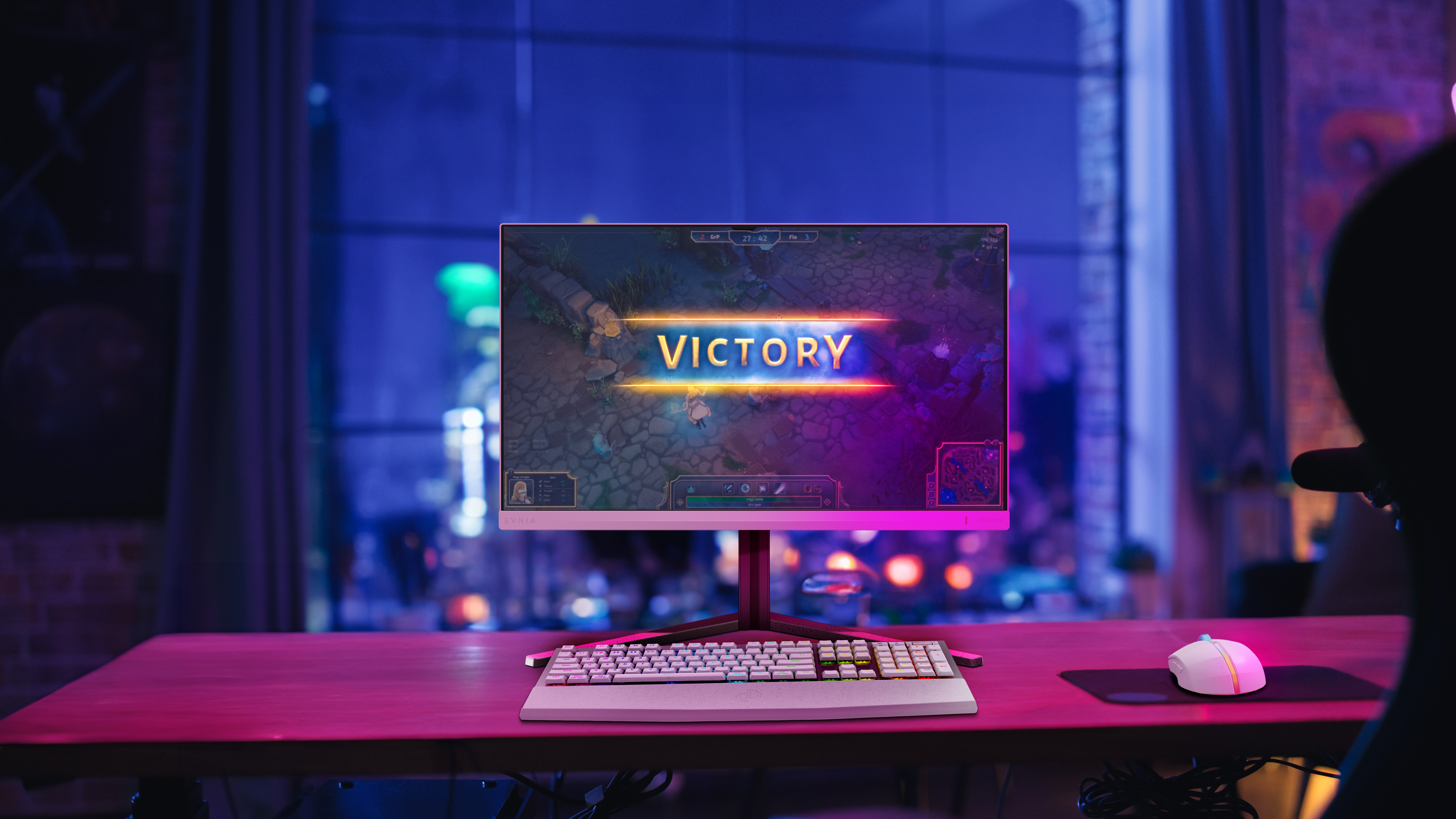 Monitor komputera wyświetlający grę ze słowem 'VICTORY', z biurkiem i oknem w tle.