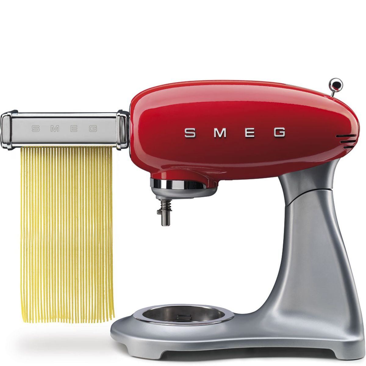 Máquina de pasta Smeg roja con pasta colgando. Tiene una base plateada y accesorios.