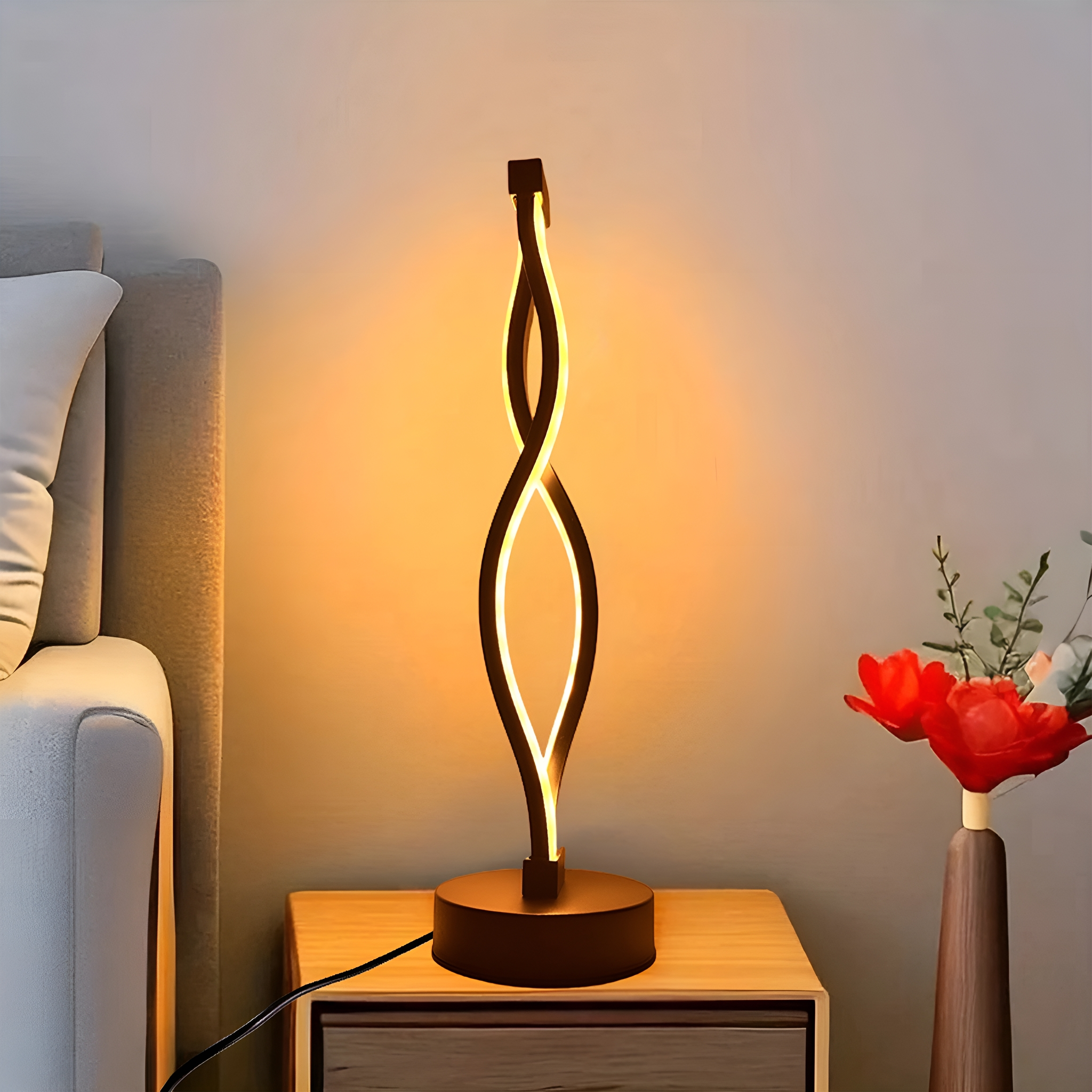 Eine dekorative Tischlampe. Die Lampe ist schwarz mit weißem Licht. Auf dem Tisch stehen Blumen.