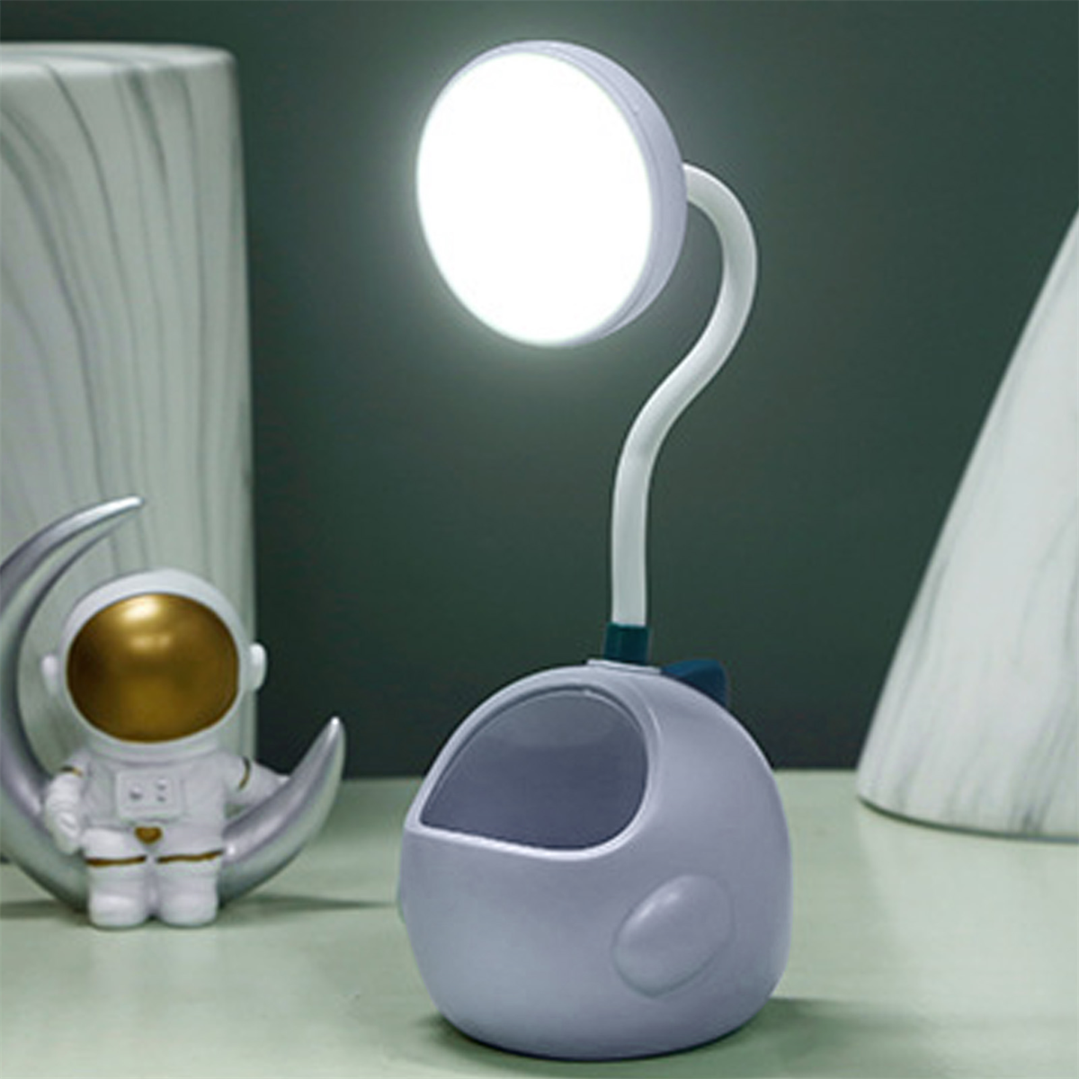 Eine schreibtischlampe in Form eines Astronauten mit einem Stifthalter.