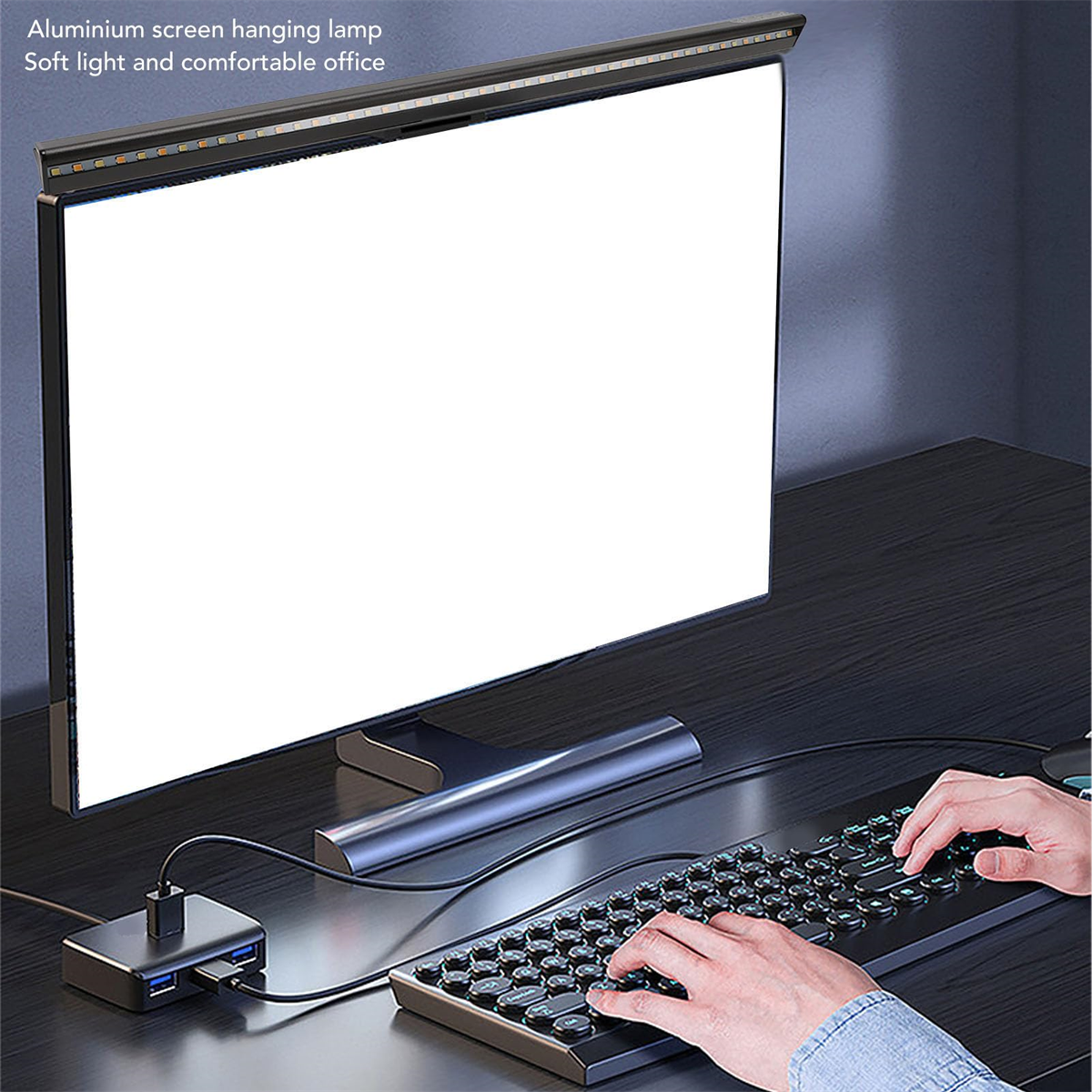 Eine Aluminium-Bildschirm-Hängeleuchte über einem Monitor mit Tastatur und Maus auf einem Schreibtisch.