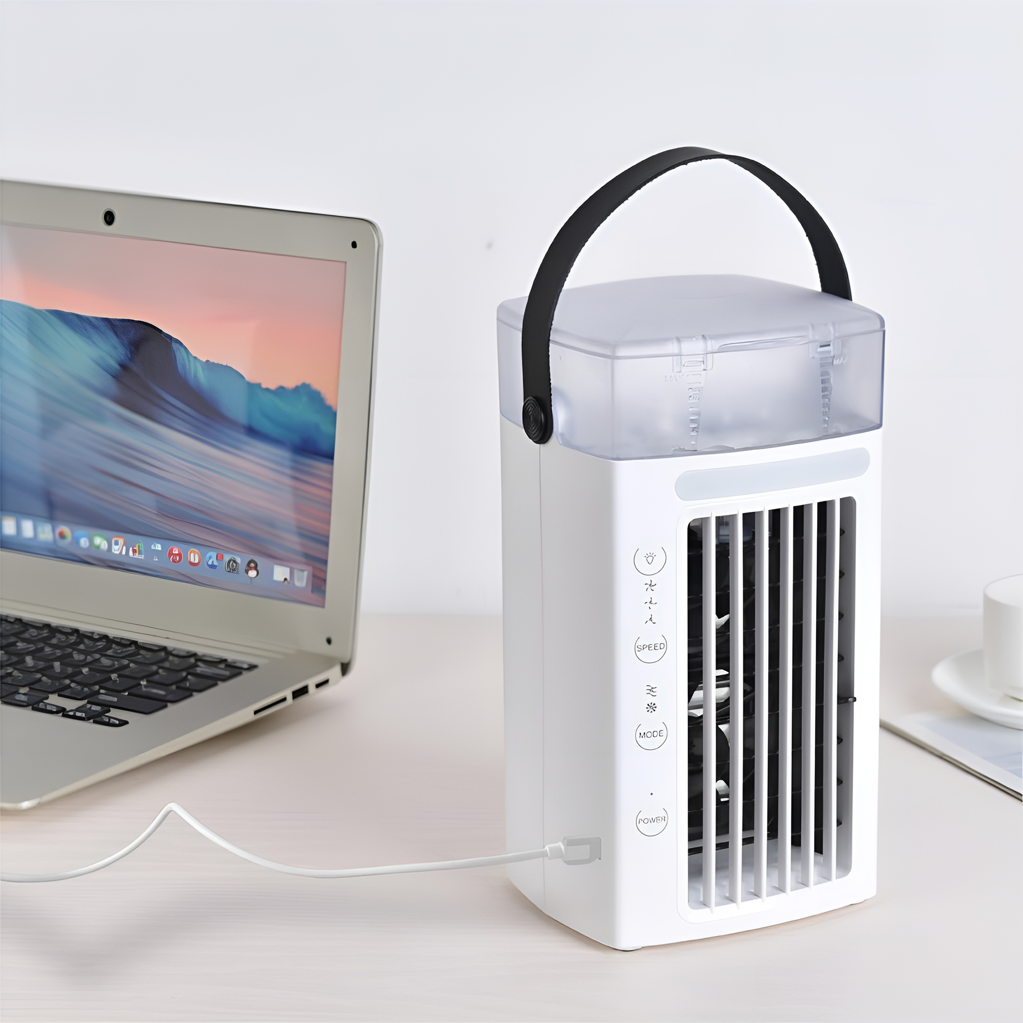 Ein weißer tragbarer Luftkühler neben einem Laptop, an eine Stromquelle angeschlossen.