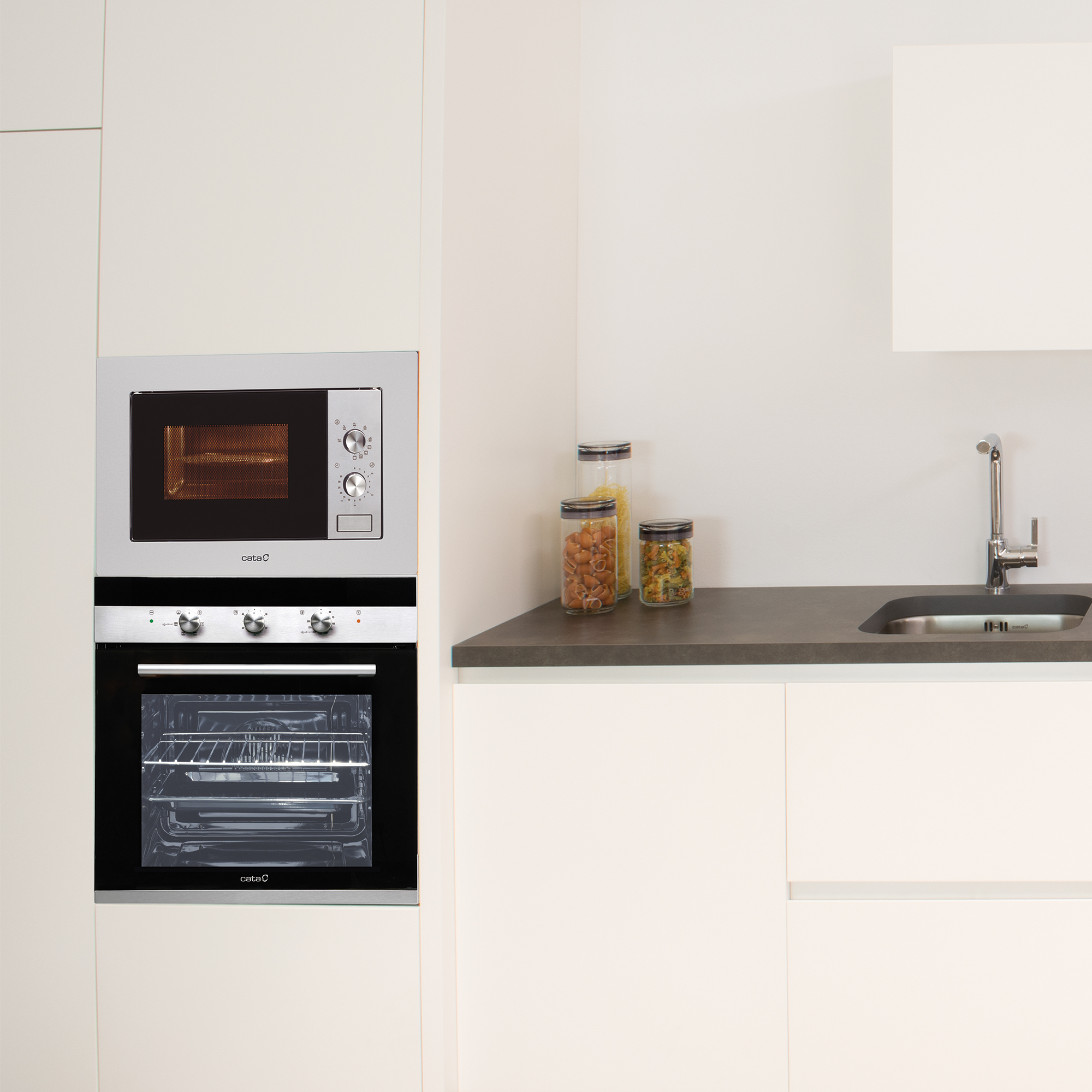 Electrodomésticos de cocina empotrados, horno y microondas, con armarios blancos y encimera.
