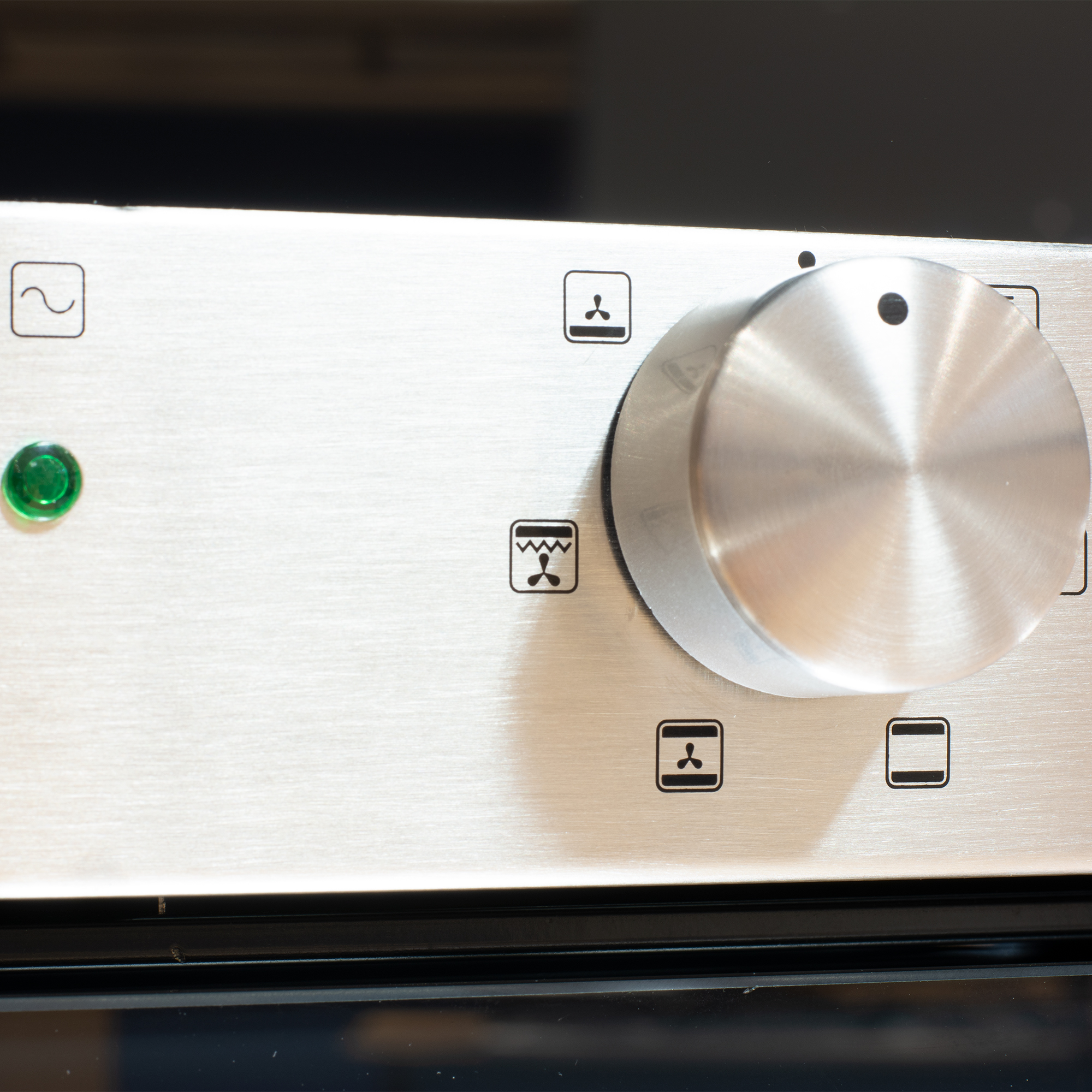 Primer plano del panel de control del horno con un dial y símbolos.