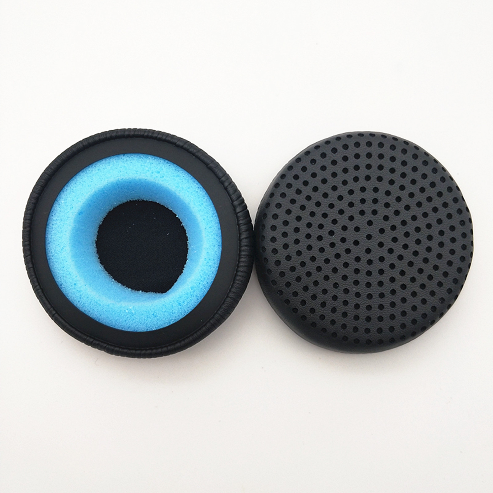 Due cuscinetti auricolari rotondi neri per cuffie. Uno ha schiuma blu e l'altro una superficie a pois.