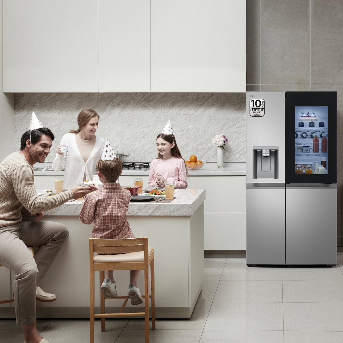 Eine Familie versammelt sich in der Küche, rechts steht ein Kühlschrank. Sie feiern.
