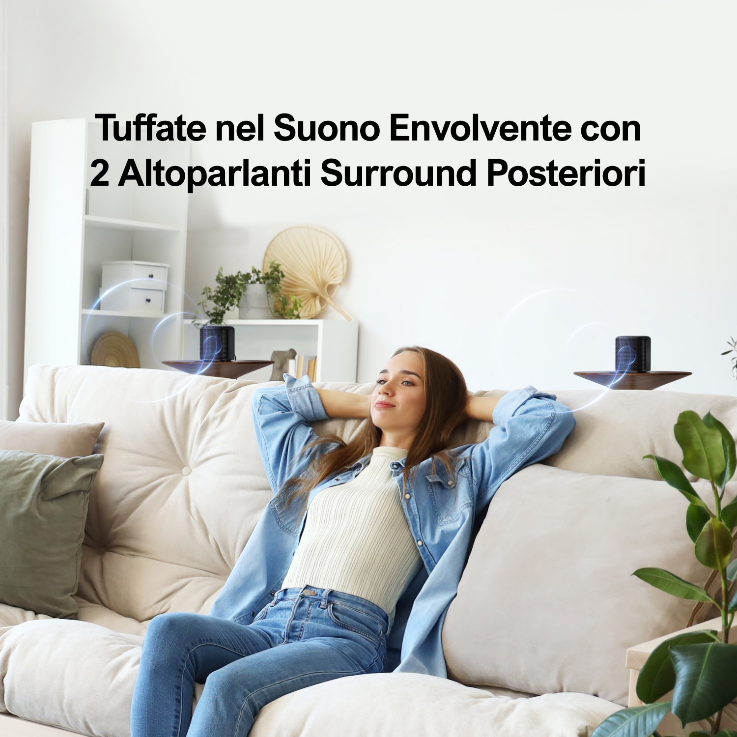 Una donna si rilassa su un divano con le mani dietro la testa. Due altoparlanti dietro. Testo: Immergiti nel suono surround.