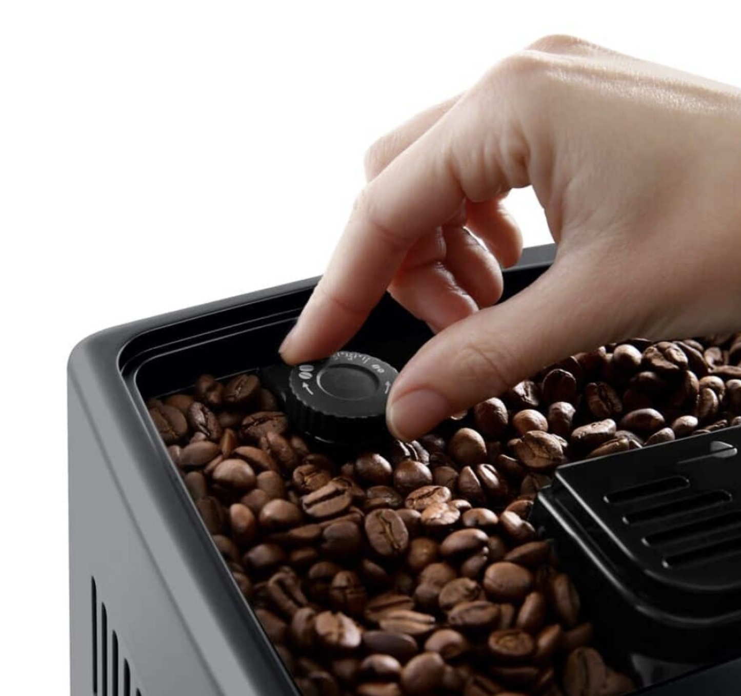 Una mano ajusta un dial negro en un recipiente de granos de café, lleno de granos marrones.