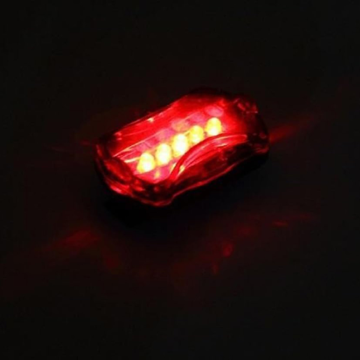 Luz roja de bicicleta con cinco luces. Está sobre un fondo negro y las luces están encendidas.
