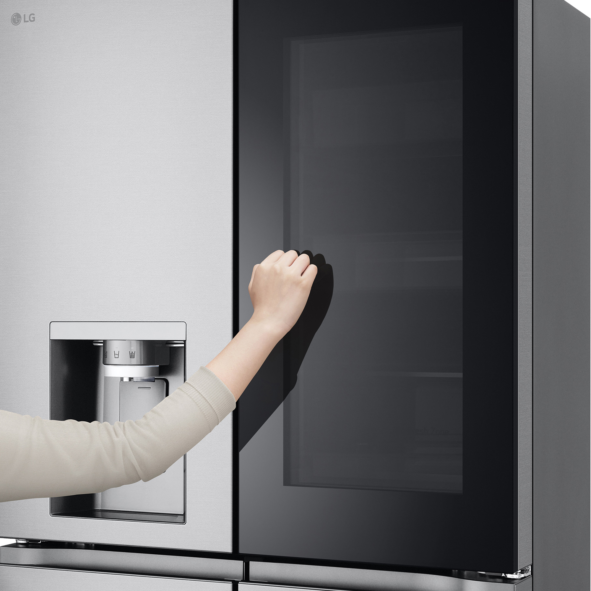 Die Hand einer Frau öffnet eine Glastür eines LG-Kühlschranks aus Edelstahl.