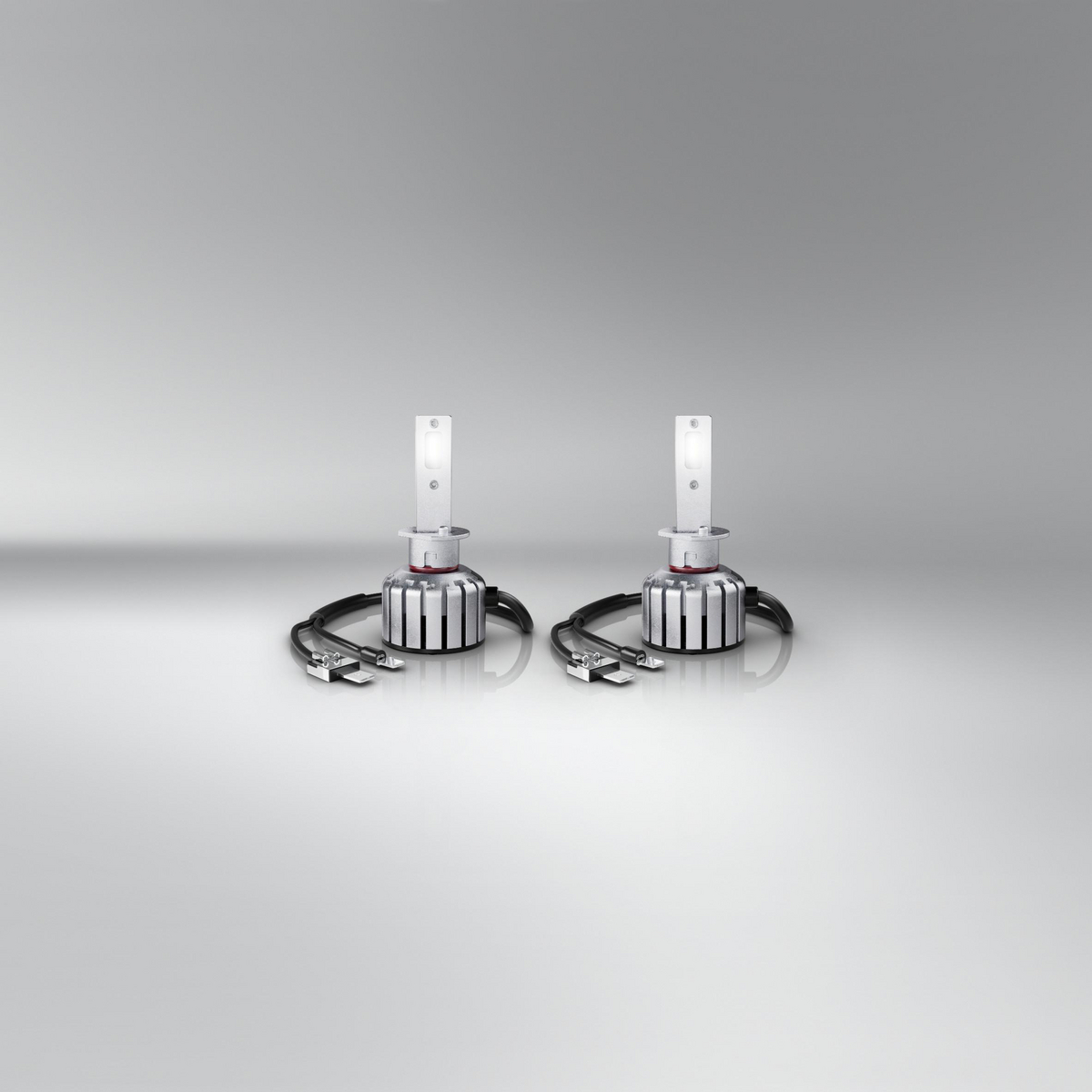 Paar Autoscheinwerfer, silber und weiß, auf hellgrauem Hintergrund.