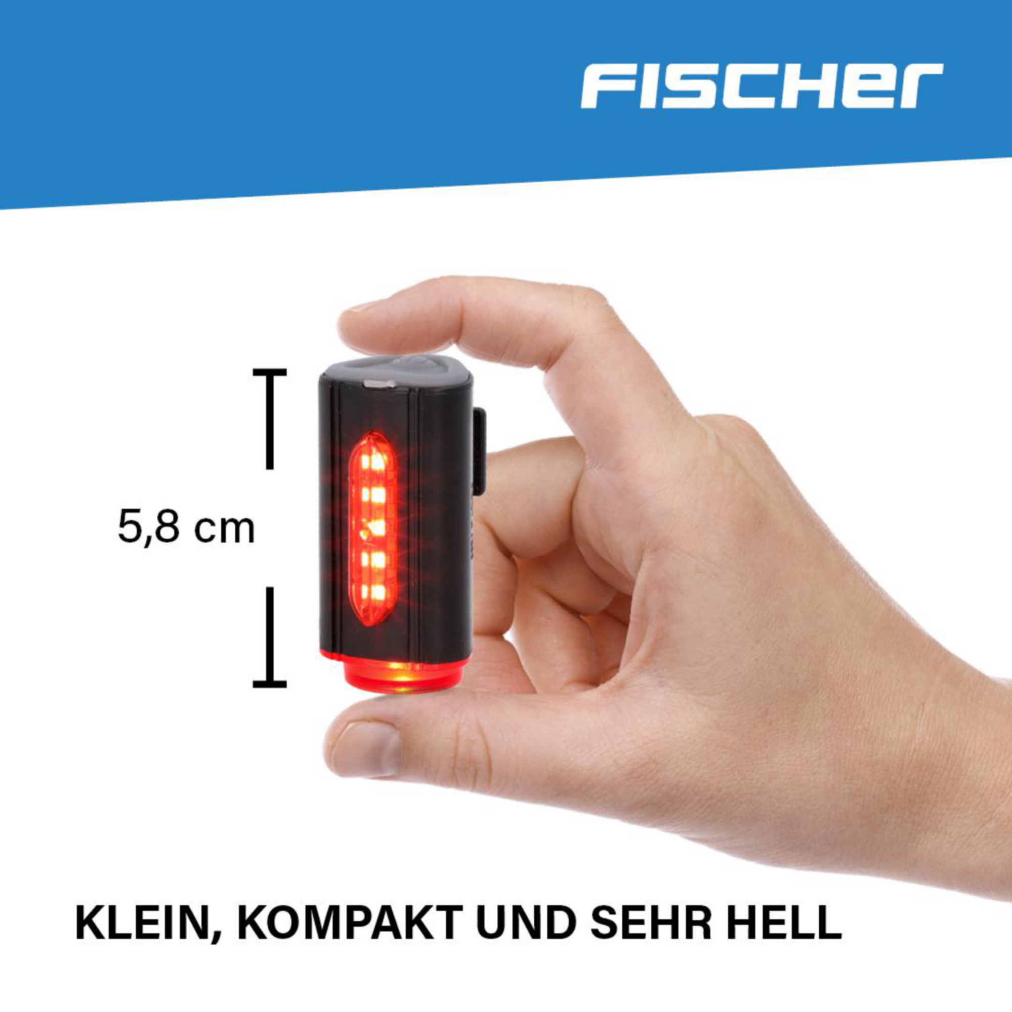 Hand, die ein kleines schwarzes Fahrradlicht mit roten LEDs hält, das Licht befindet sich neben einem Lineal.