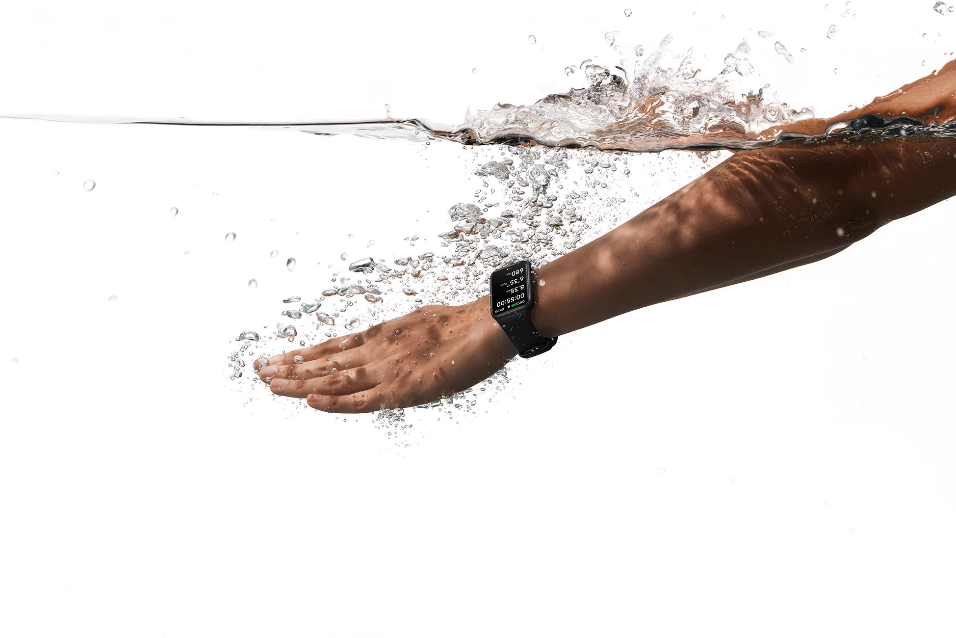Brazo de persona con reloj inteligente en el agua, mano extendida, con burbujas y salpicaduras de agua.