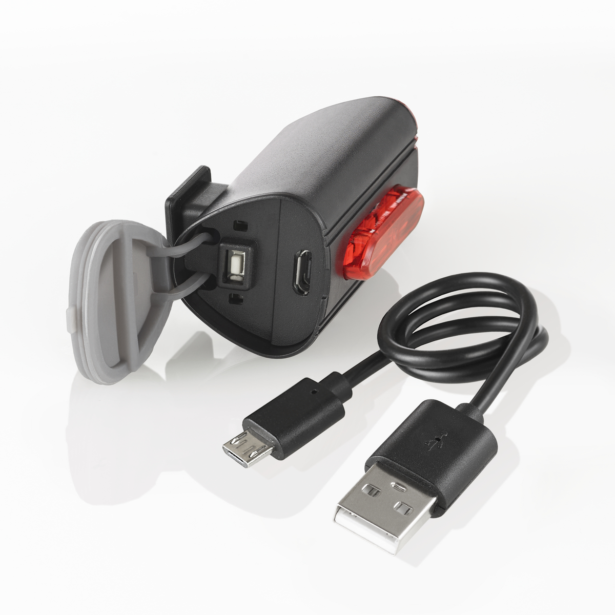 Schwarzes Fahrradlicht mit USB-Anschluss und Ladekabel. Das Licht hat eine rote Linse.
